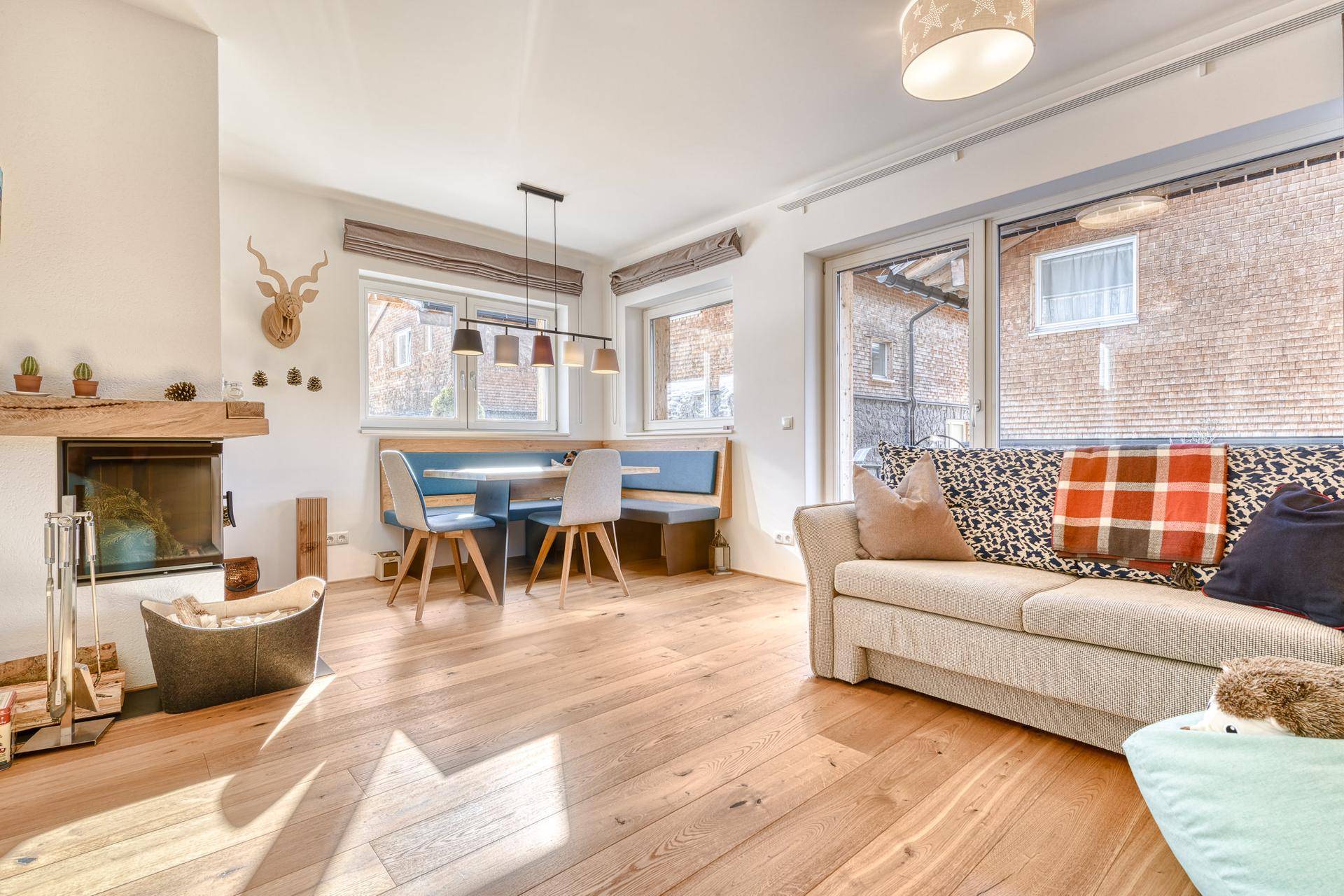 Helles Wohn-Esszimmer mit Holzboden, Kamin und gemütlicher Sitzecke am Fenster.