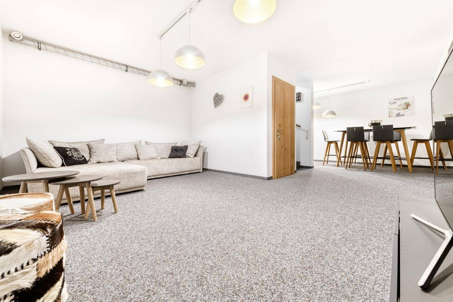 Geräumiges Wohnzimmer mit Teppichboden, großem Sofa und moderner Einrichtung.