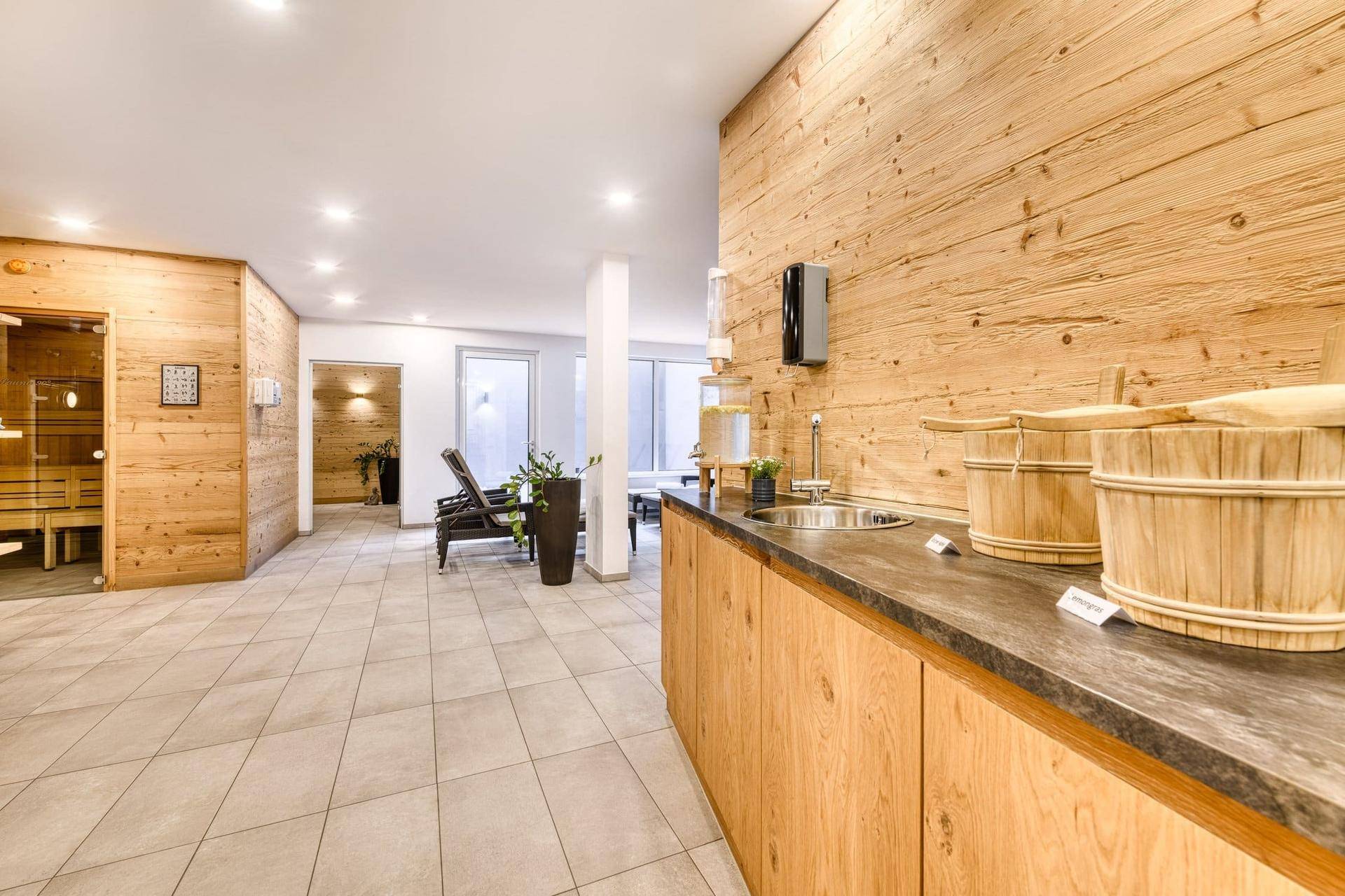 Moderner Wellnessbereich mit Holzverkleidung, Entspannungsliegen und Zugang zur Sauna.
