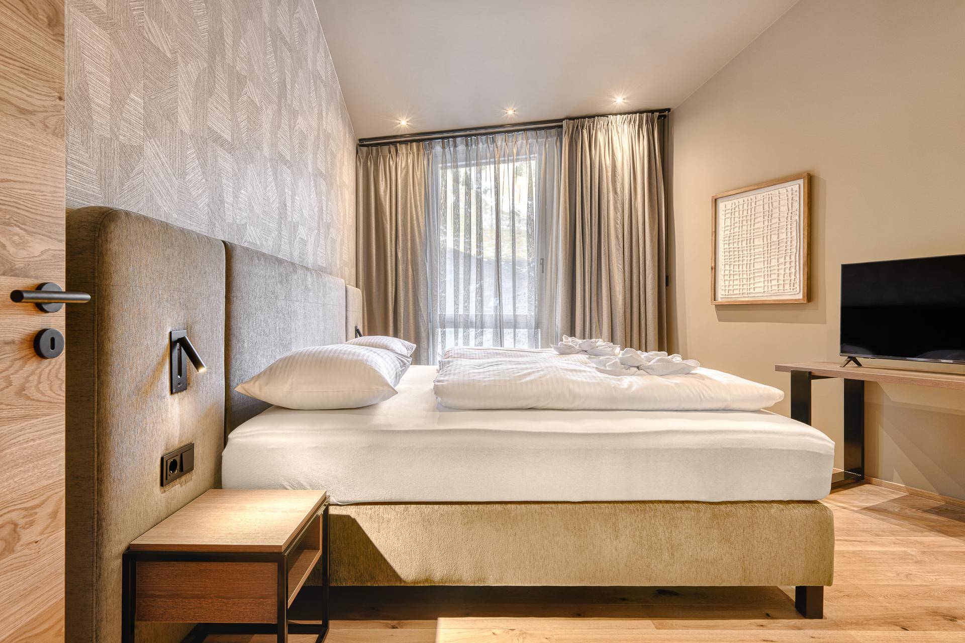 Gemütliches Schlafzimmer mit Doppelbett, Holzboden und Vorhängen, die für Privatsphäre sorgen.