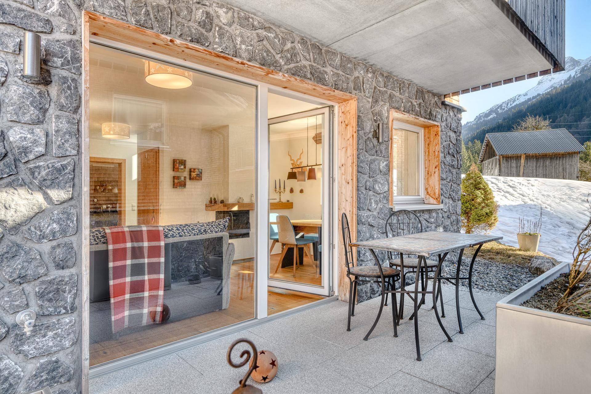 Gemütliche Terrasse mit Steinfliesen und Gartenmöbeln, direkt am Haus mit Bergblick.