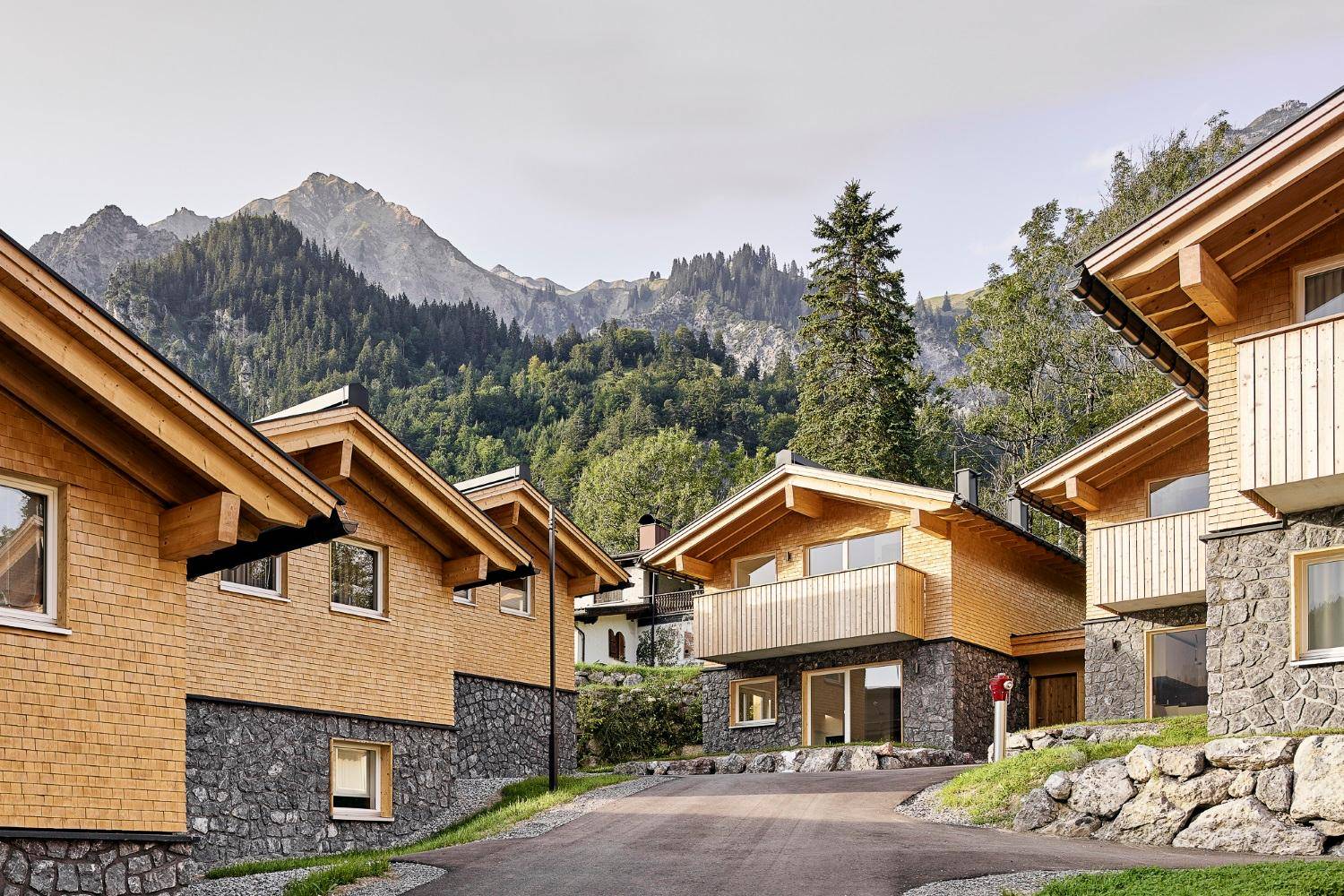 Anwesen mit mehreren Holzchalets in einer grünen Berglandschaft unter klarem Himmel.