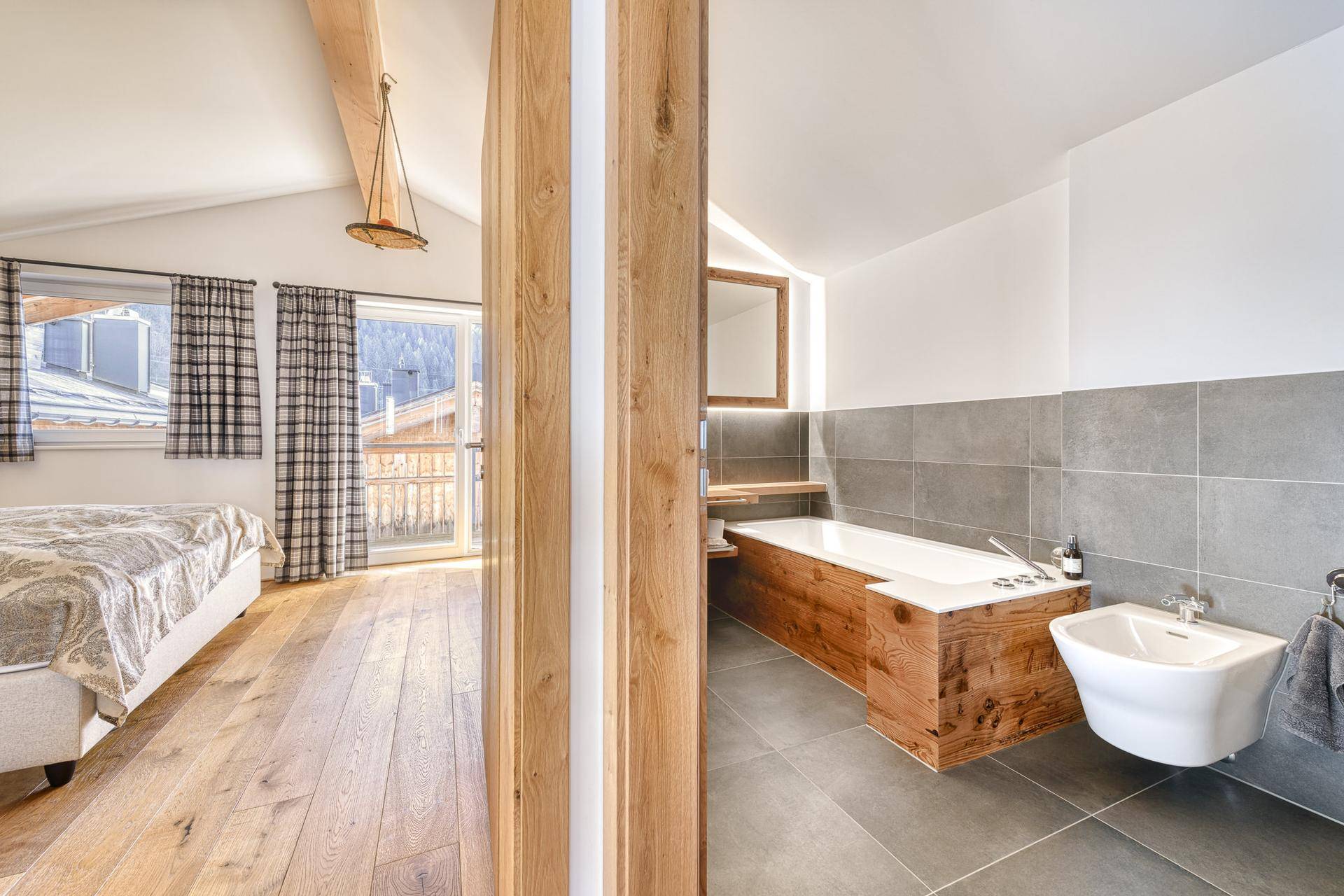 Modernes Badezimmer mit Holzverkleidung, Badewanne und Bidet, direkt an ein Schlafzimmer angrenzend.