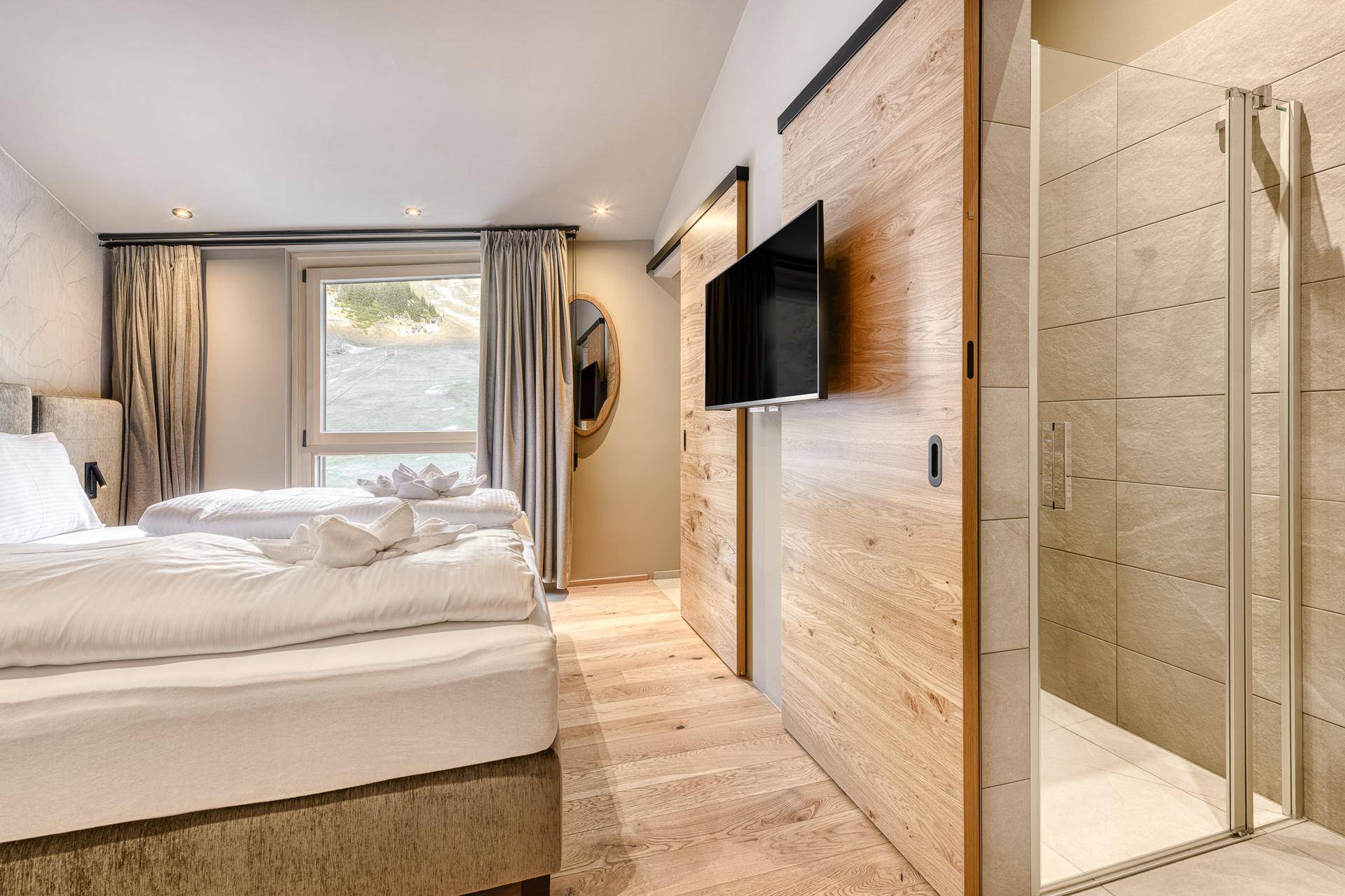 Modernes Schlafzimmer mit Holzboden, Doppelbett und integrierter Duschkabine.