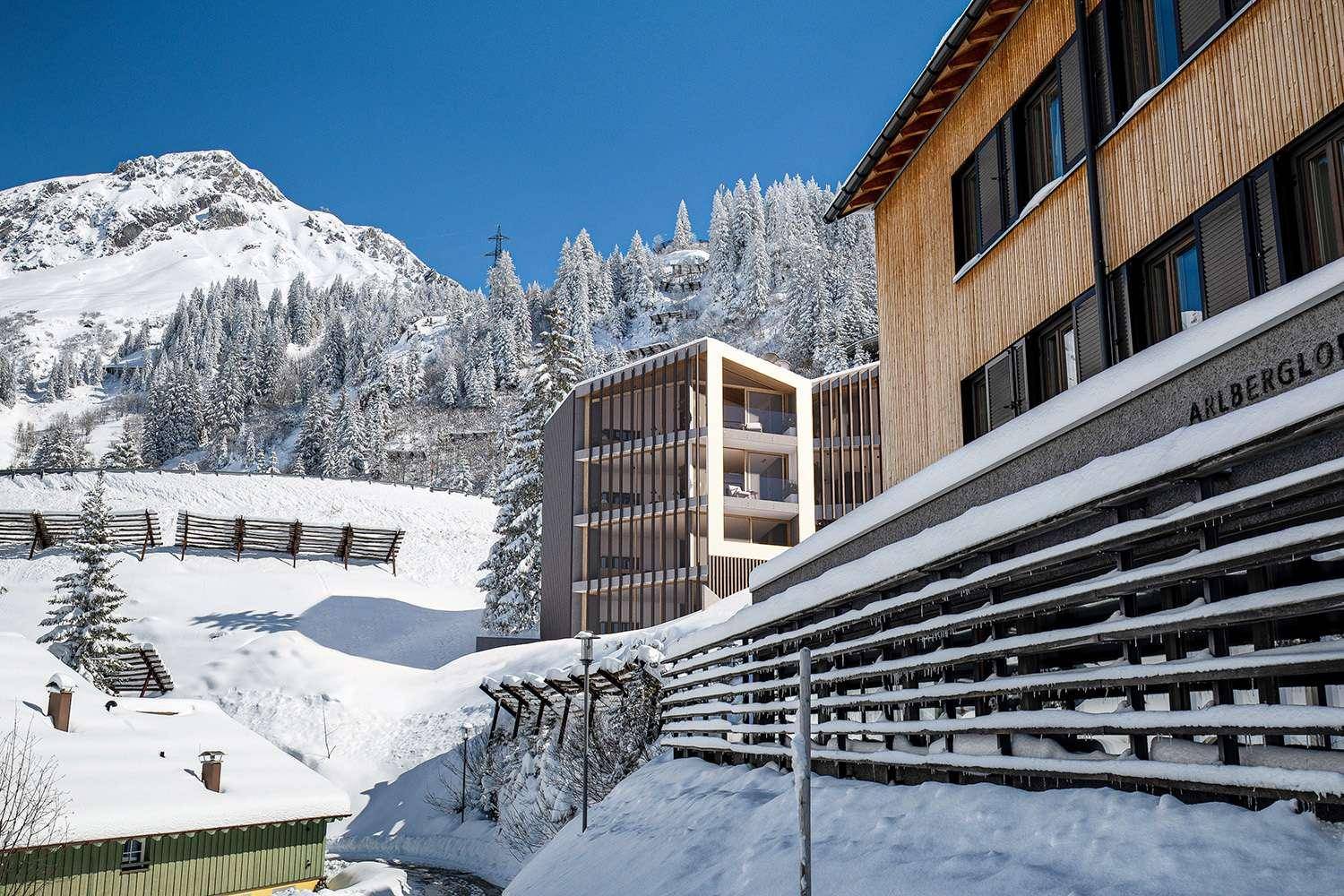 Modernes Gebäude in alpiner Umgebung, umgeben von Schnee und Bergen.
