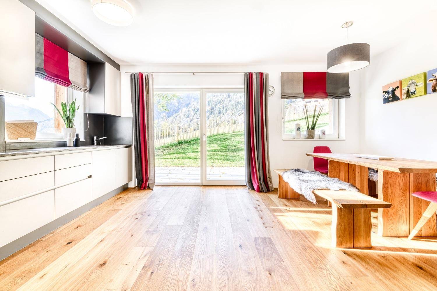 Heller Wohn-Essbereich mit Holzboden, moderner Küche und Zugang zum Garten.