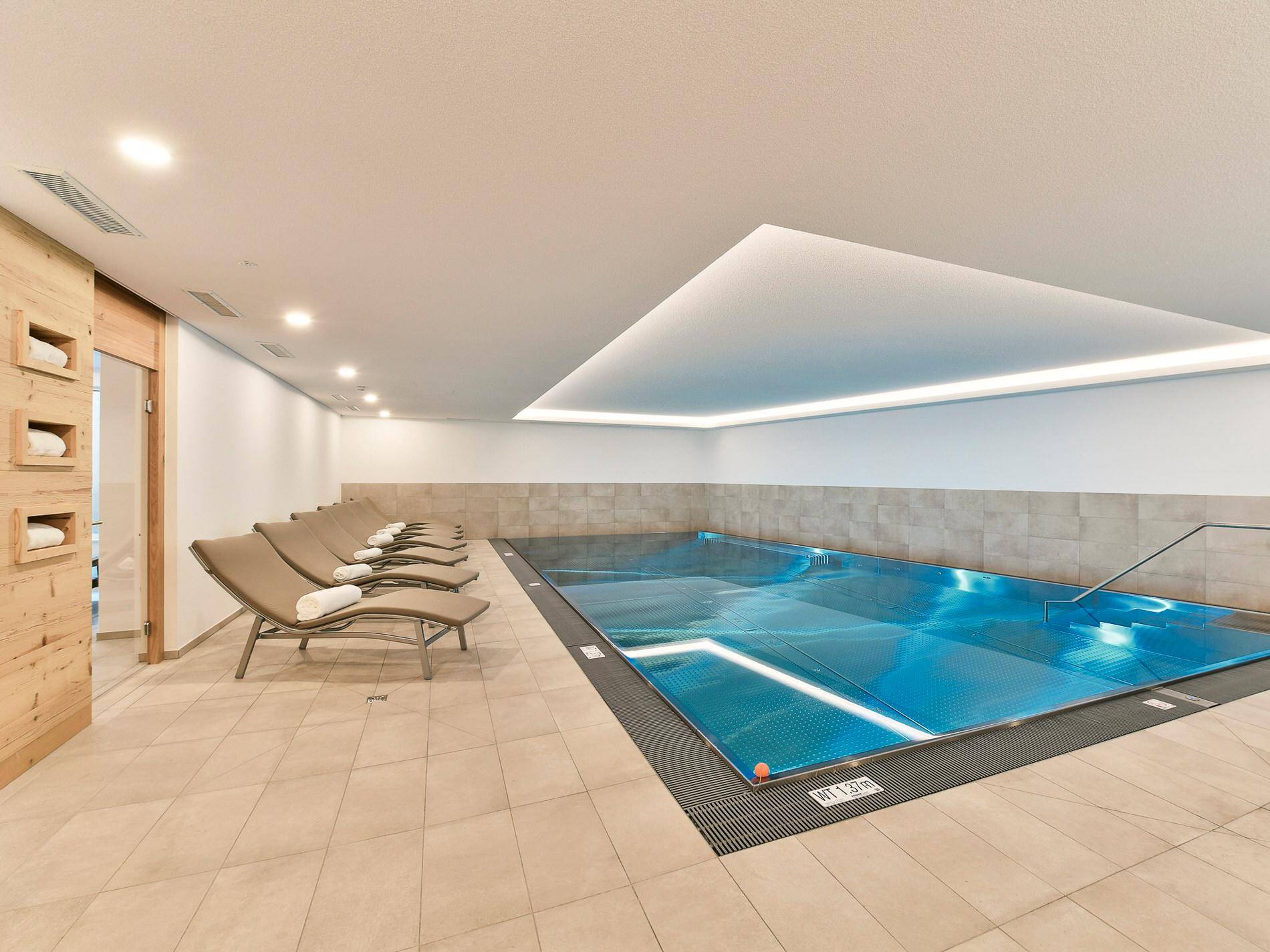 Hallenbadbereich mit Liegestühlen und einem modernen Schwimmbecken, ideal zur Entspannung.