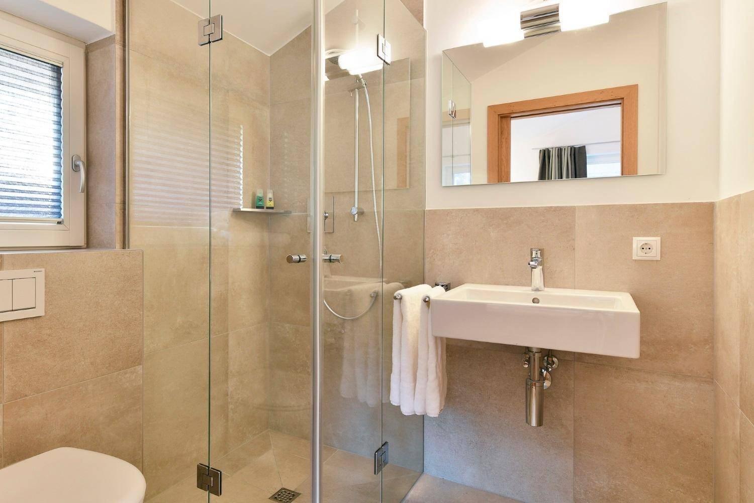 Modernes Badezimmer mit begehbarer Dusche, Wand-WC und Waschbecken.