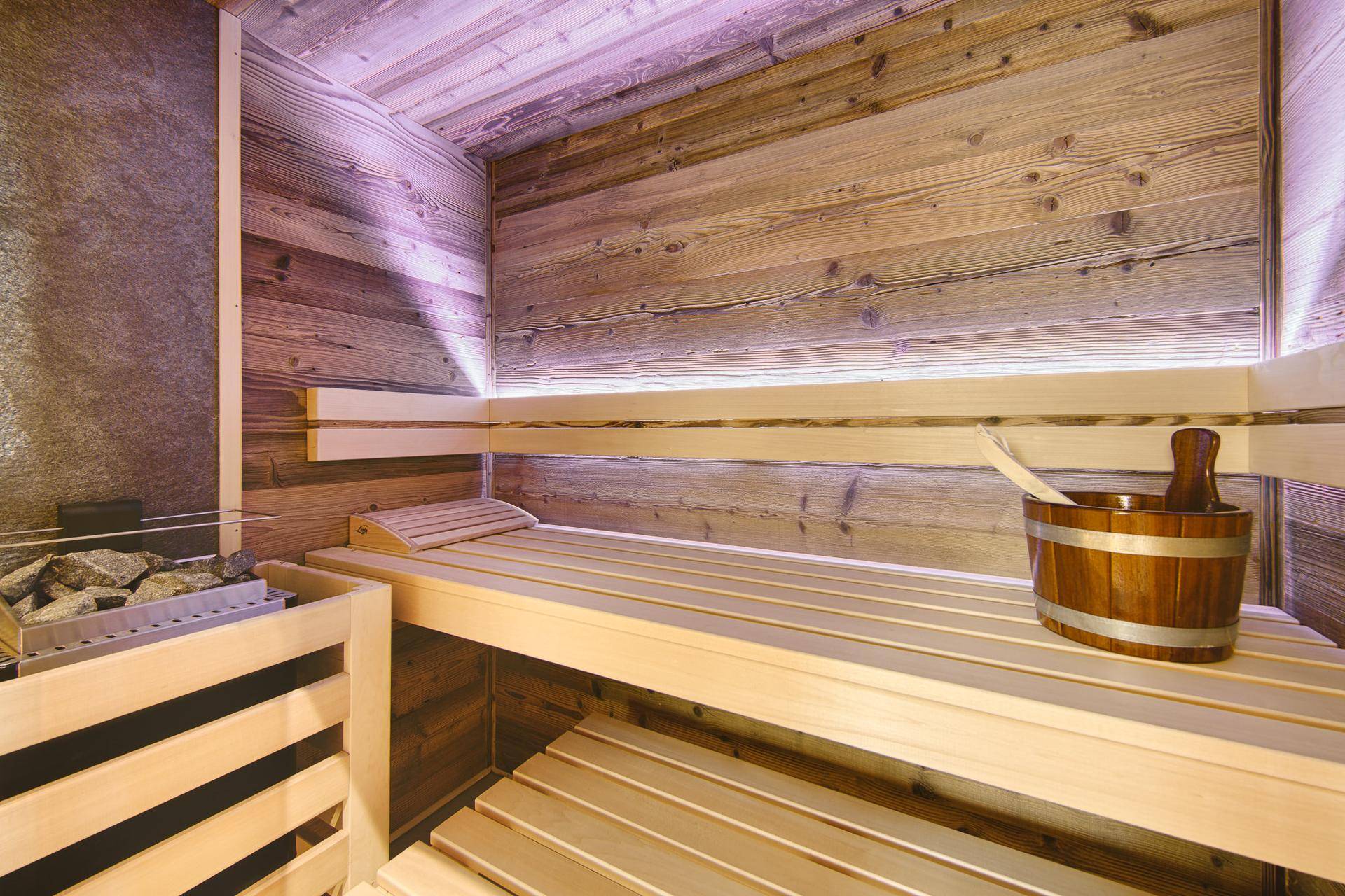 Gemütliche Holzsauna mit Bänken und traditionellem Saunaofen für Entspannung.