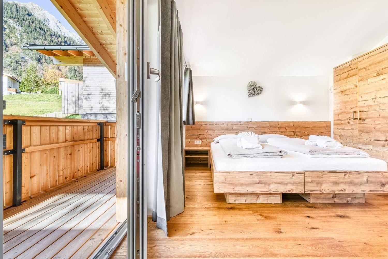 Helles Schlafzimmer mit Holzboden, Doppelbett und Zugang zum Balkon.