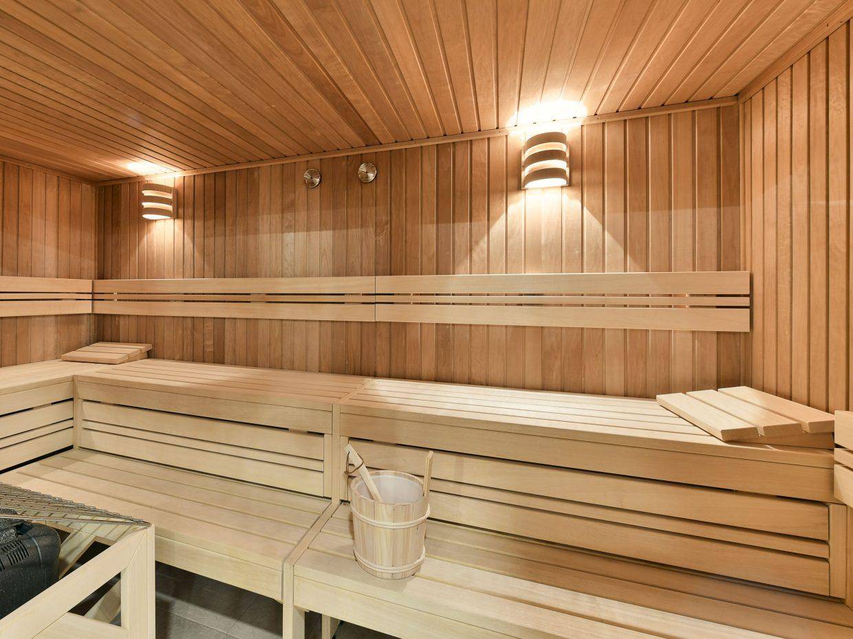 Geräumige Holzsauna mit mehreren Sitzbänken und indirekter Beleuchtung für entspannende Momente.
