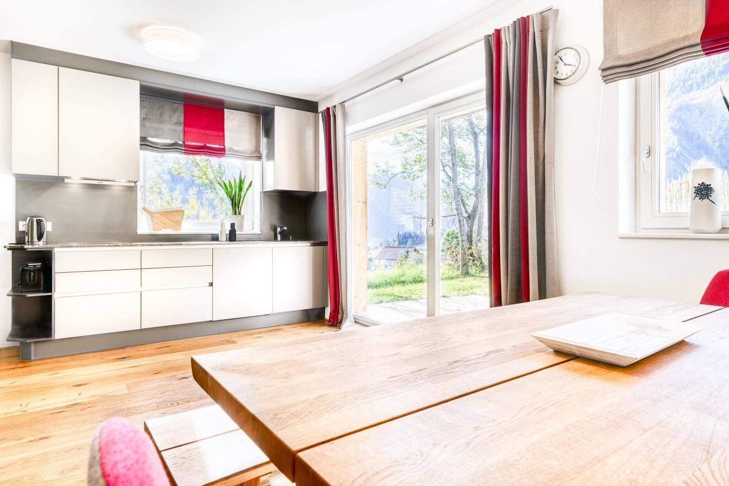 Helle Küche mit Holzboden, Esstisch und Zugang zum Garten.