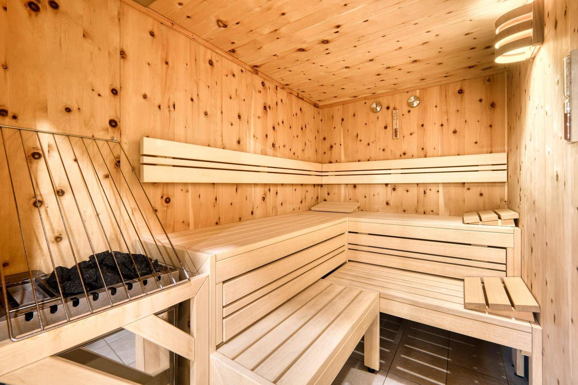 Geräumige Holzsauna mit mehreren Bänken und einem Saunaofen für entspannende Momente.