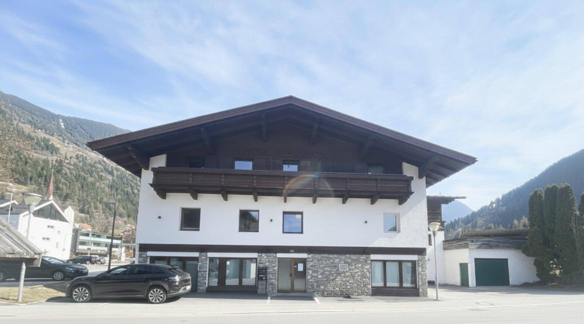 Ansicht des Gebäudes mit traditioneller Holzverkleidung und Steinakzenten im Erdgeschoss.