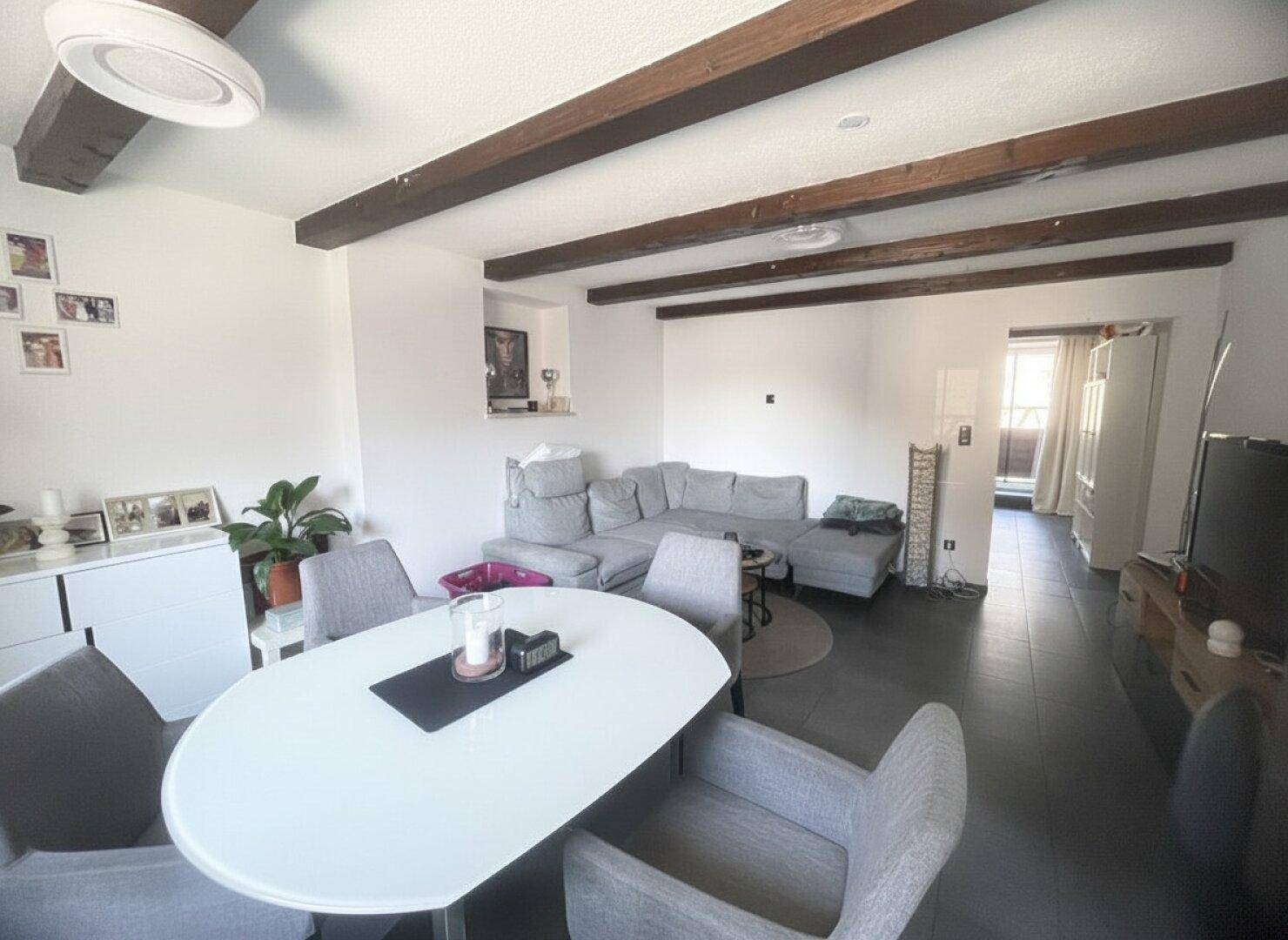 Geräumiger Wohn-Essbereich mit Holzbalken, großem Esstisch und gemütlicher Sitzecke.