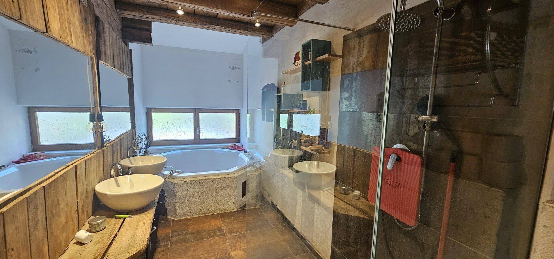 Modernes Badezimmer mit Eckbadewanne, zwei Waschbecken und rustikalen Holzverkleidungen.