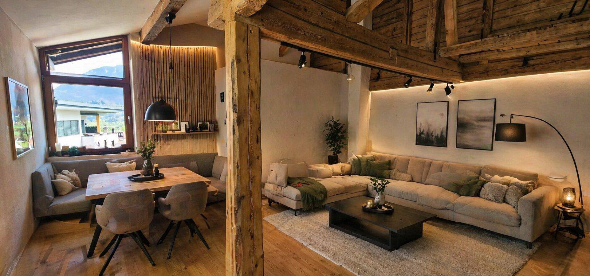 Geräumiger Wohn-Essbereich mit großem Sofa, Essecke und weitem Blick auf die umliegenden Berge.