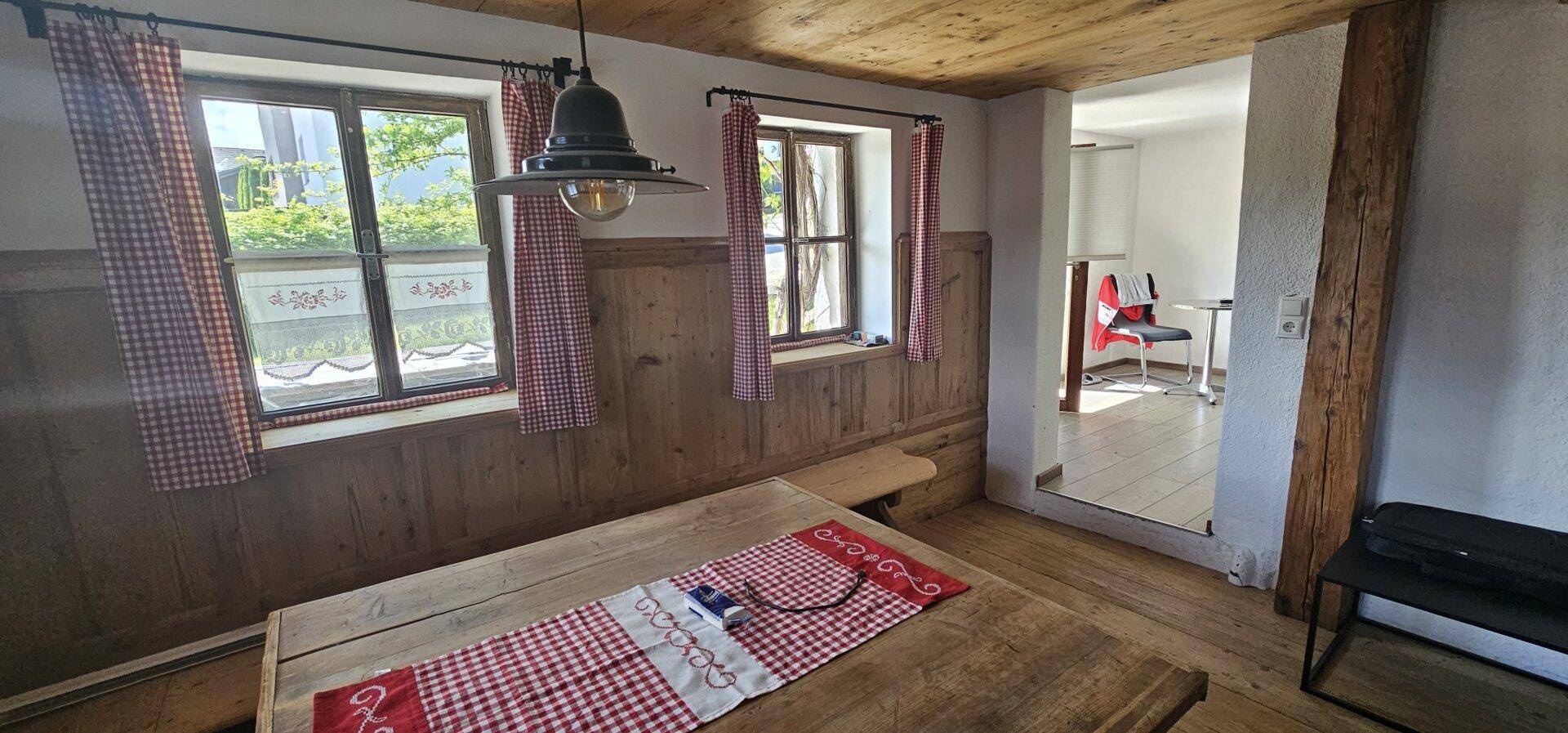 Gemütlicher Essbereich im alpinen Stil mit massivem Holztisch, Holzvertäfelung und karierten Vorhängen.