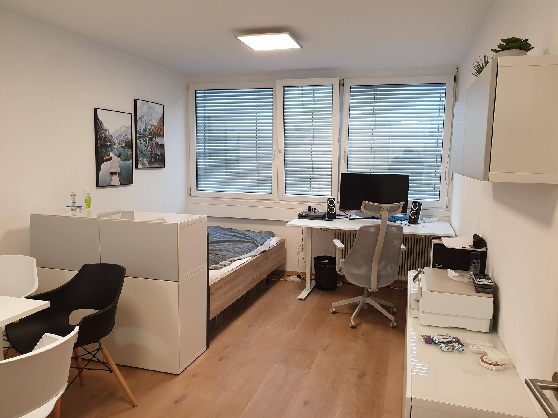 Kombiniertes Schlaf- und Arbeitszimmer mit Bett, Schreibtisch und Holzfußboden.