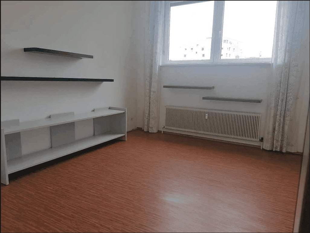 Heller Raum mit großem Fenster, Heizkörper, schwebenden Regalen und einem warmen, rötlich-braunen Boden.