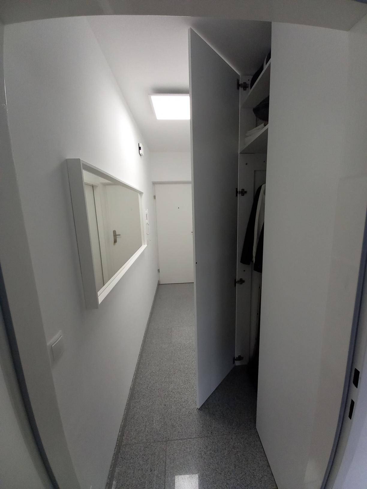 Schmaler Flur mit integrierten Schränken und einem Wandspiegel für mehr Raumgefühl.