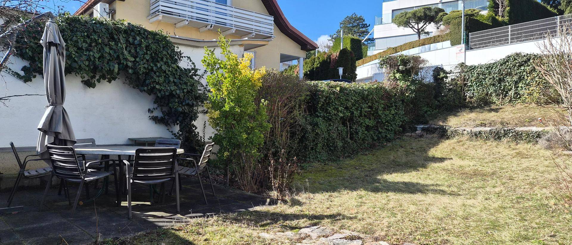 Gemütlicher Sitzbereich im Garten mit Tisch und Stühlen, ideal für Mahlzeiten im Freien.