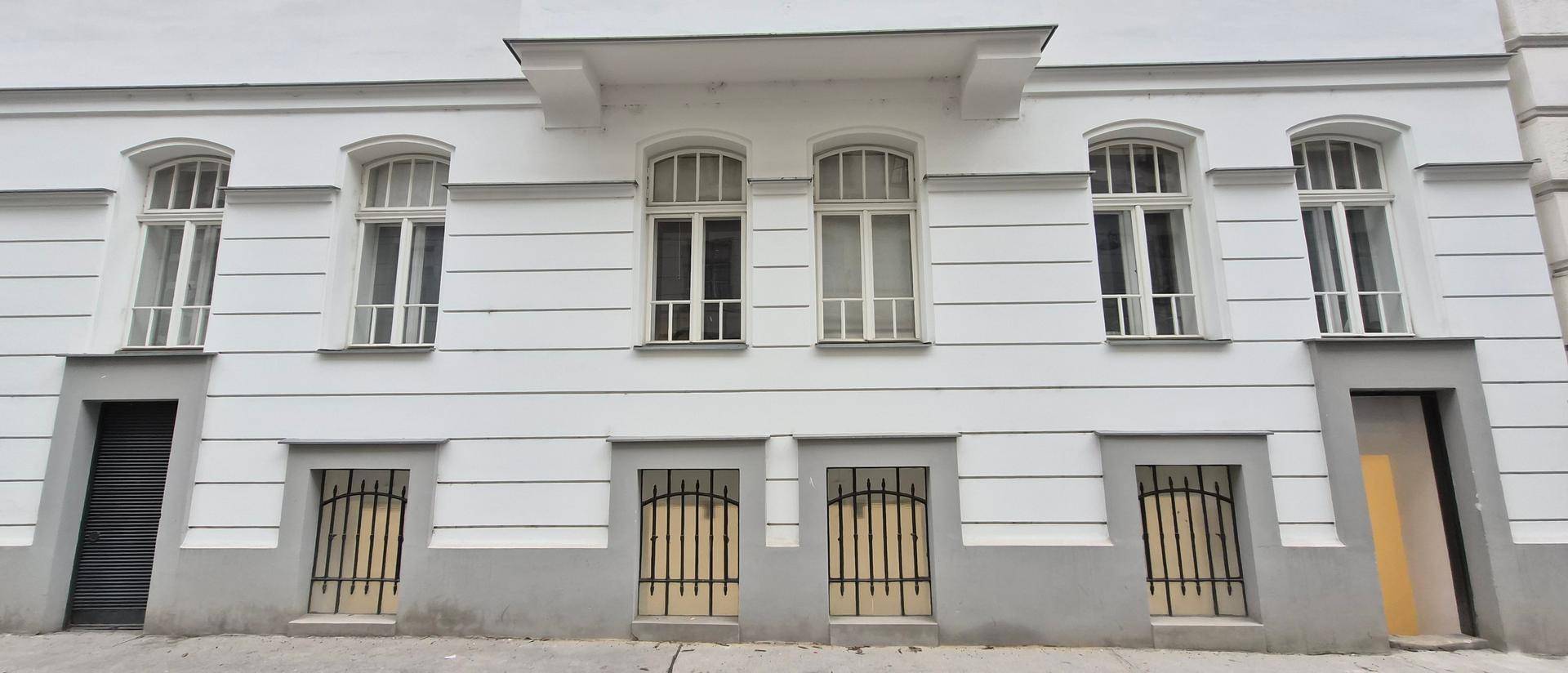 Klassische Fassade eines Altbaus mit großen Fenstern und modernisierten Elementen.