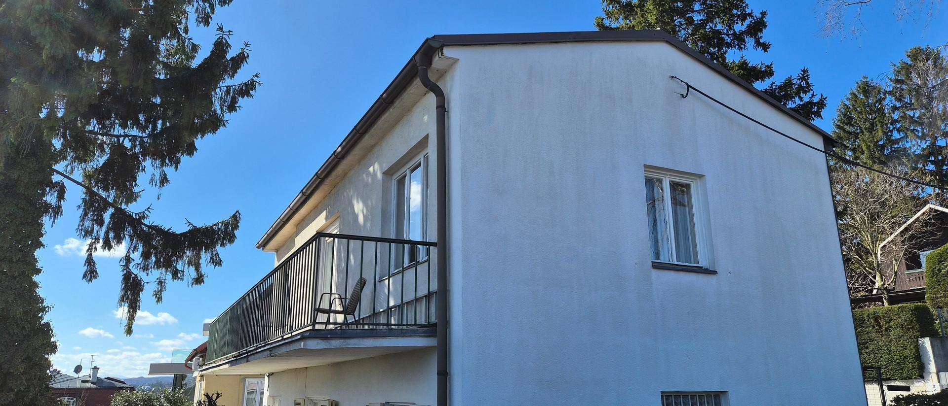 Rückansicht des Hauses mit einem Balkon und Blick auf die umliegende grüne Landschaft.