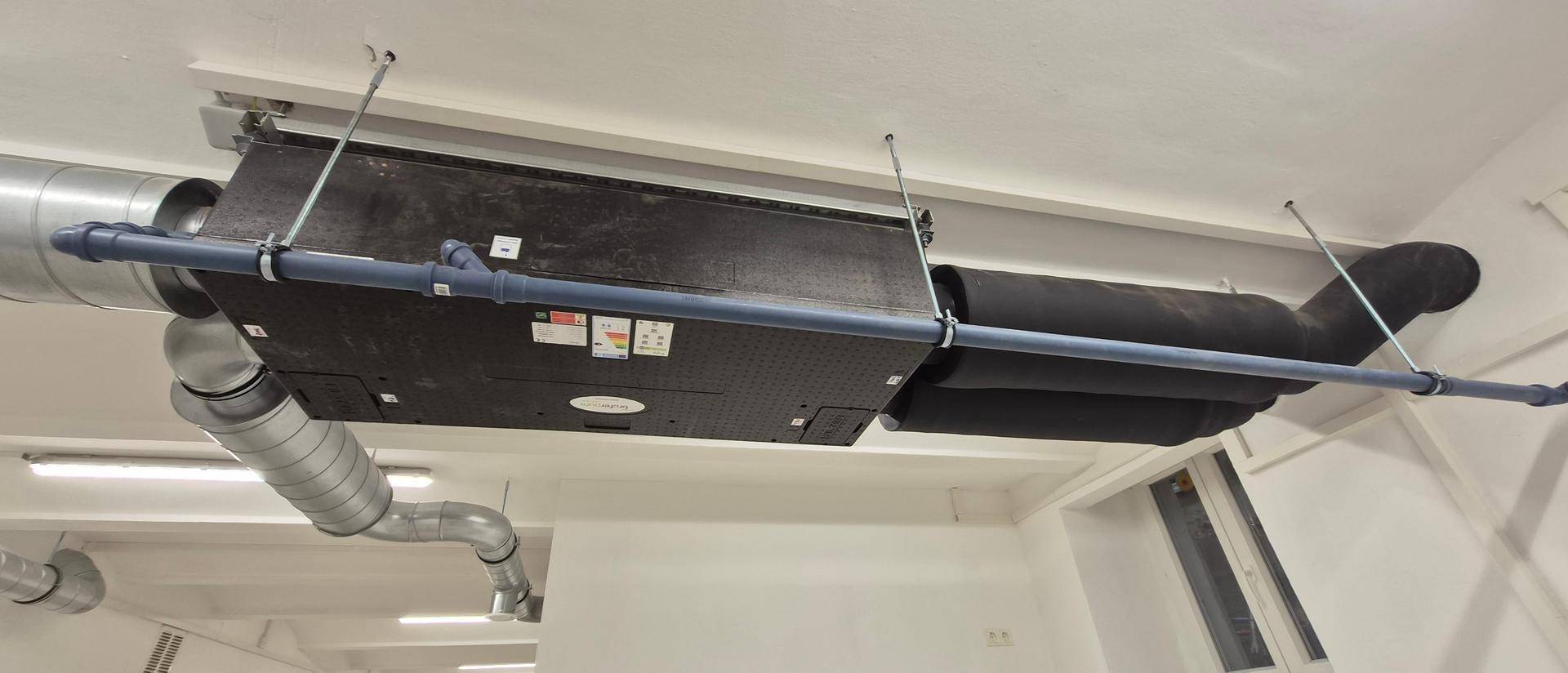 Nahaufnahme eines modernen Lüftungssystems mit Rohren und Kanälen, an der Decke montiert.