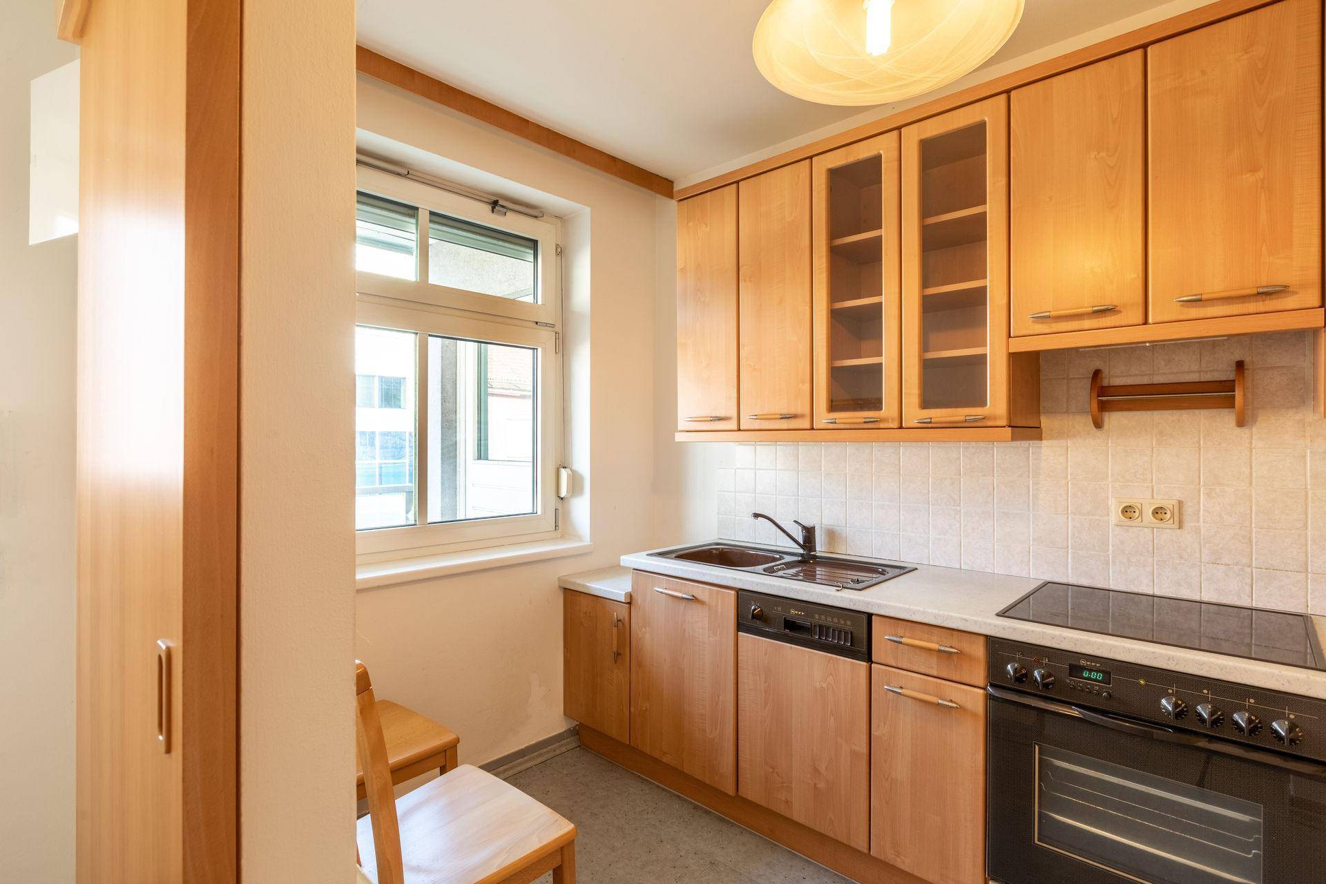 Funktionale Küche mit Holzschränken, Fenster und integrierten Geräten, ideal für den Alltag.