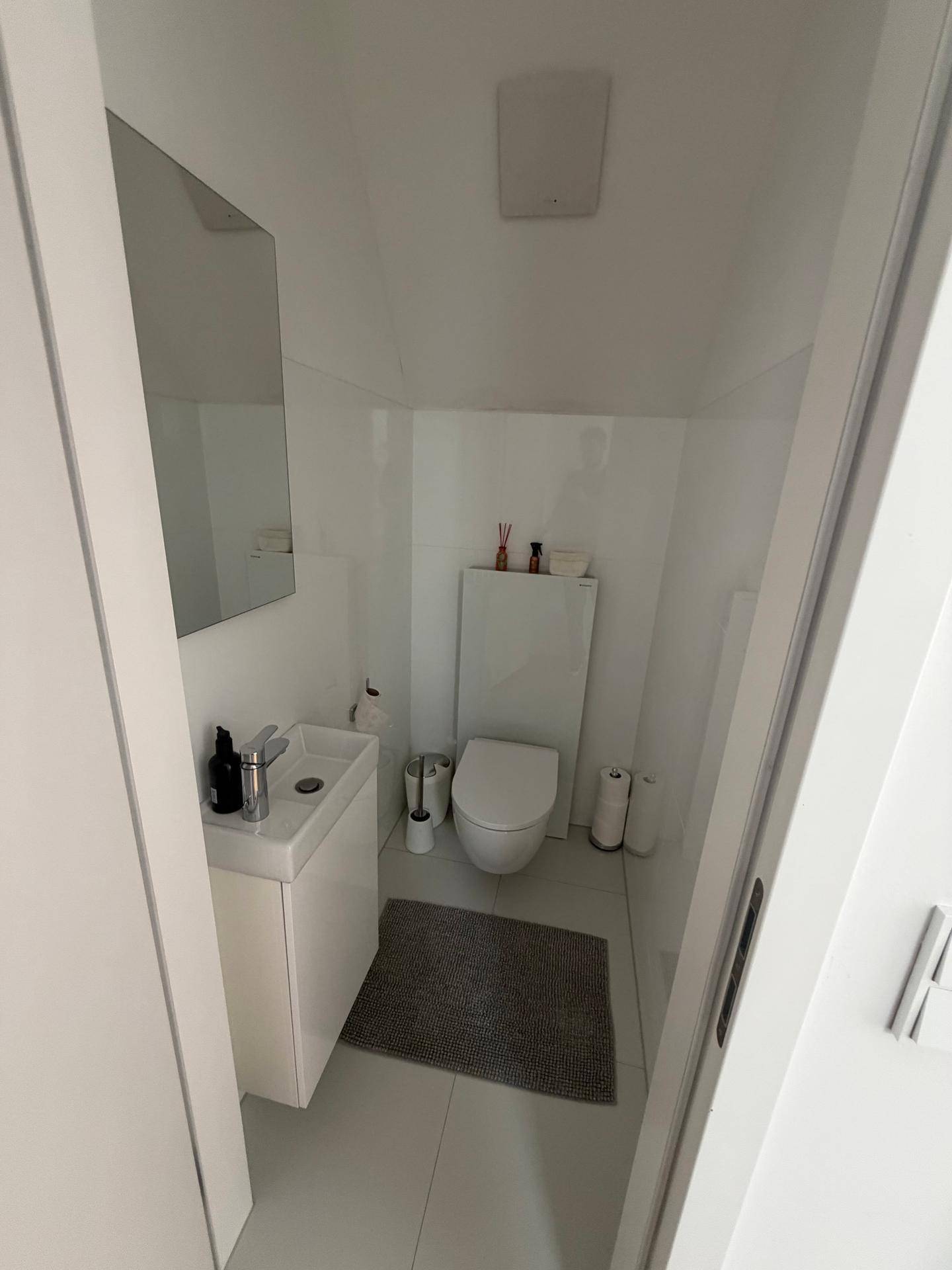 Kleines, helles Gäste-WC mit modernem Waschbecken und wandhängender Toilette.