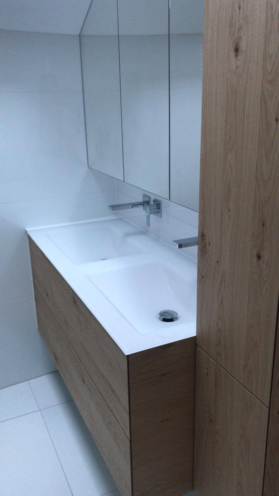 Modernes Badezimmer mit Doppelwaschbecken, Holzunterschrank und großem Spiegelschrank.
