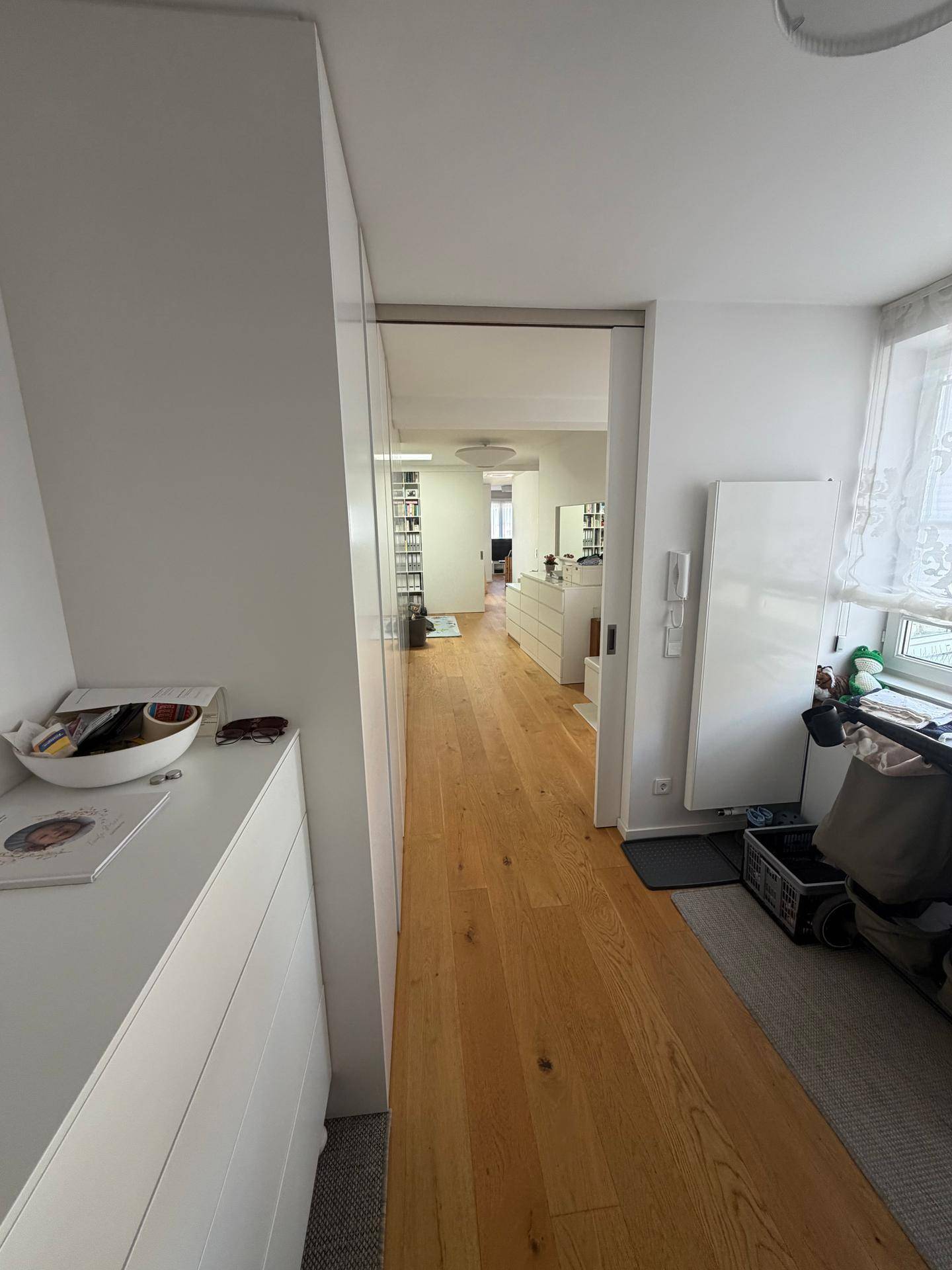 Heller Flur mit Holzboden, der zu den verschiedenen Zimmern der Wohnung führt.