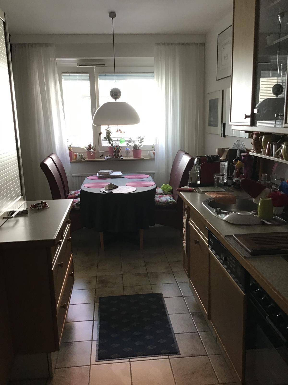Helle Wohnküche mit Esstisch, Fenster und gefliestem Boden, bietet viel Tageslicht.