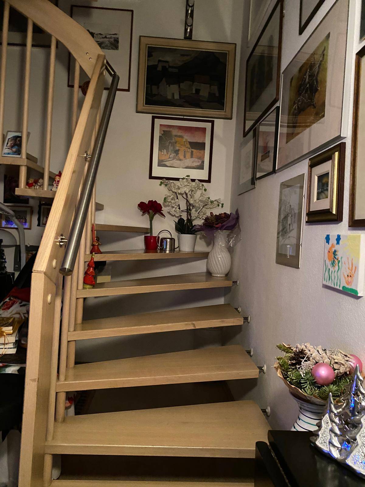 Hölzerne Wendeltreppe mit Metallgeländer und dekorativen Elementen an der Wand.