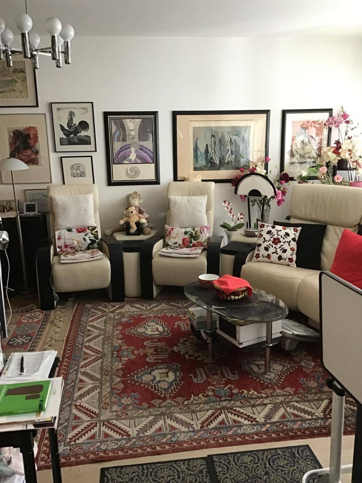 Helles Wohnzimmer mit bequemen Sesseln, Sofa und einer Wand voller gerahmter Kunstwerke.