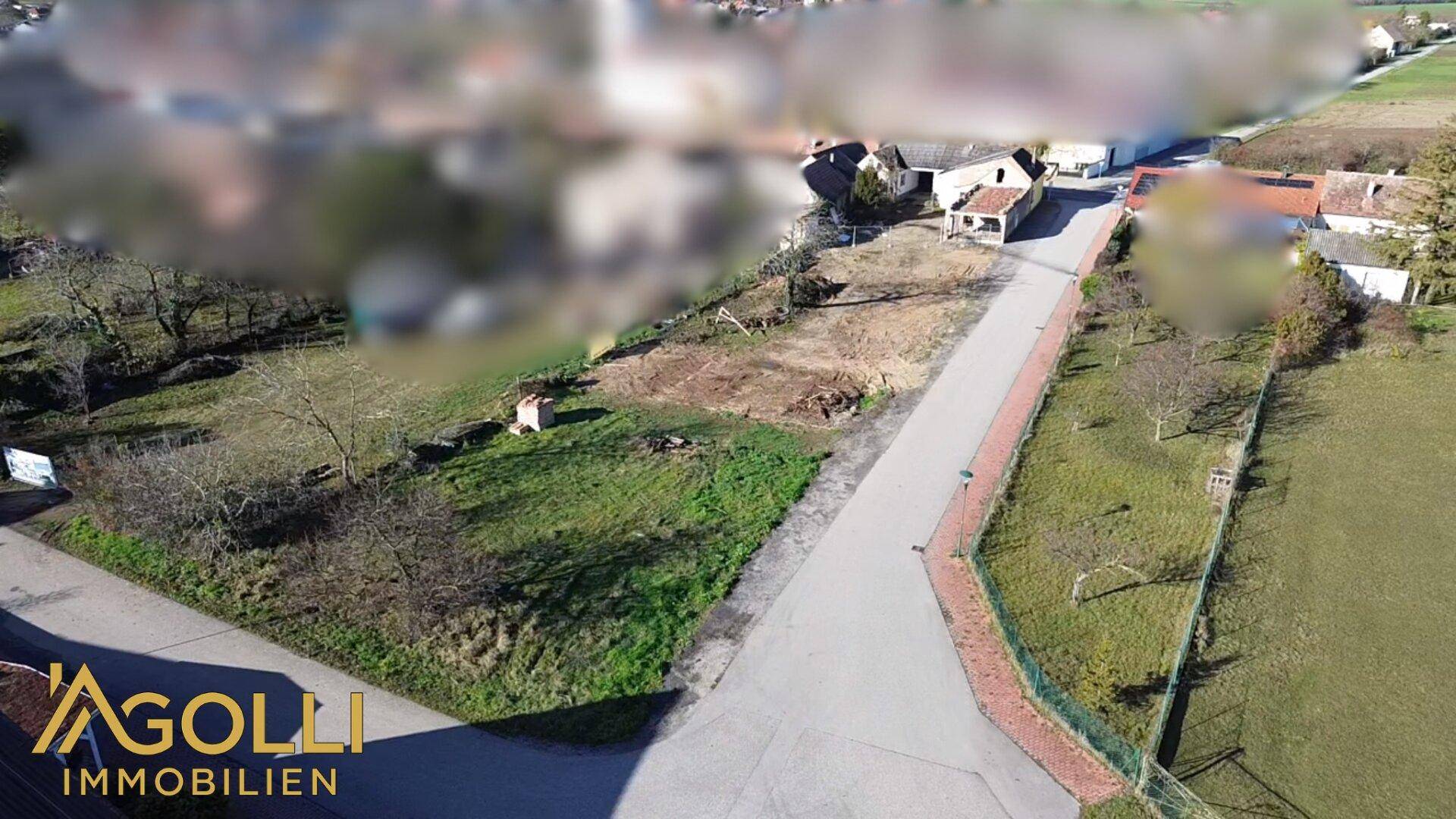 Luftaufnahme eines unbebauten Grundstücks in ländlicher Umgebung mit angrenzenden Häusern.