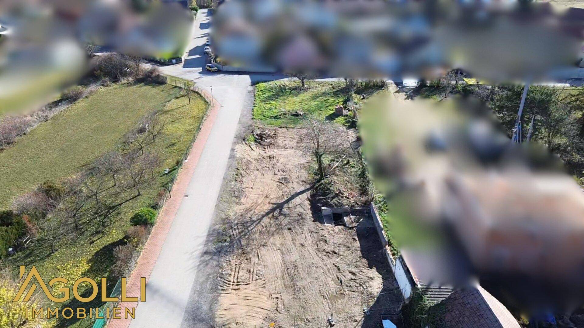 Luftaufnahme eines geräumten Grundstücks, bereit für die Bebauung, umgeben von Grünflächen.