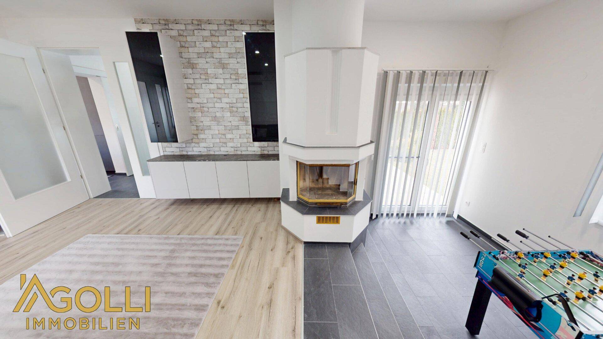 Wohnbereich mit modernem Kamin, hellem Laminatboden und Zugang zur Terrasse.