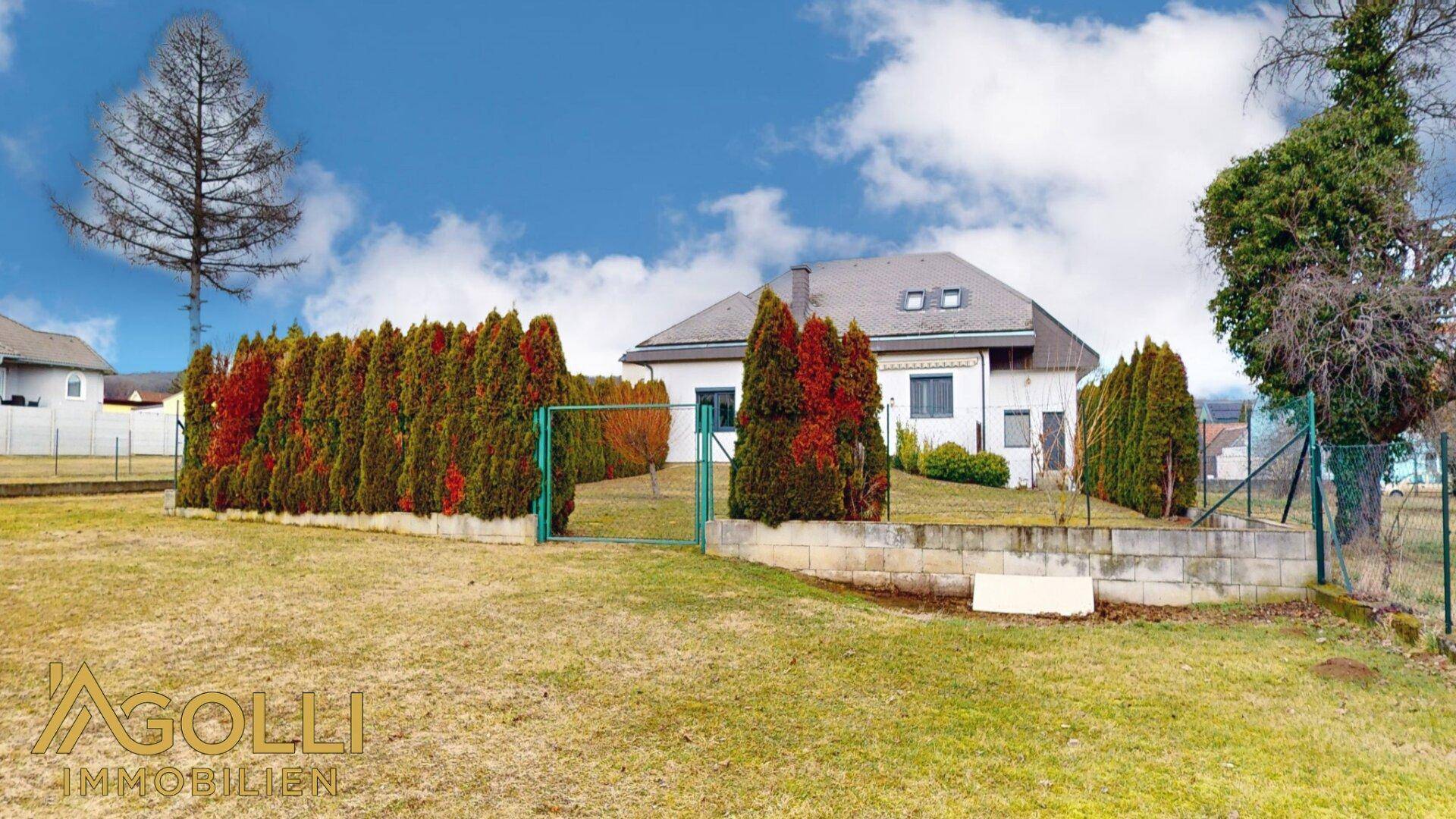 Weitläufiger Gartenbereich mit Rasenfläche, Hecken und Blick auf das Haus.