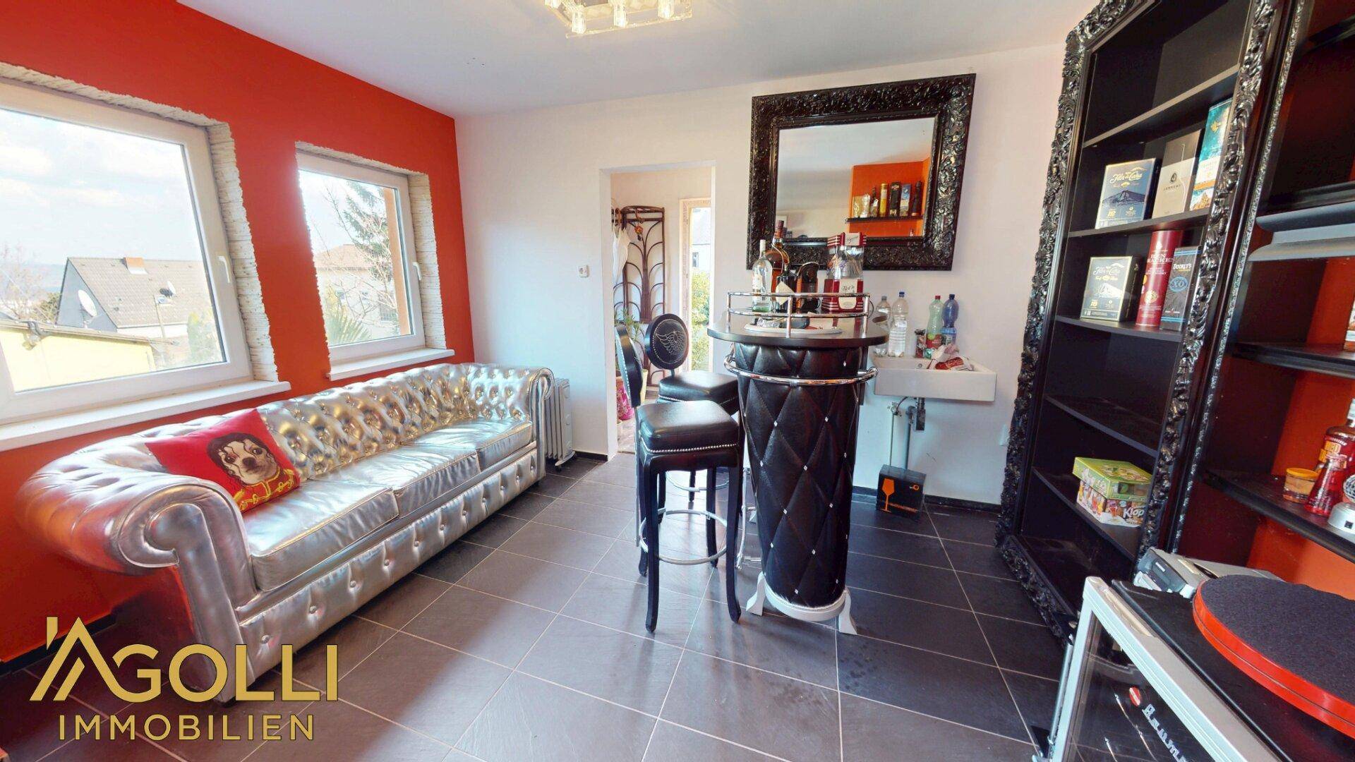 Unterhaltungsraum mit stilvoller Bar, bequemer Couch und dunklem Fliesenboden, ideal für gesellige Abende.