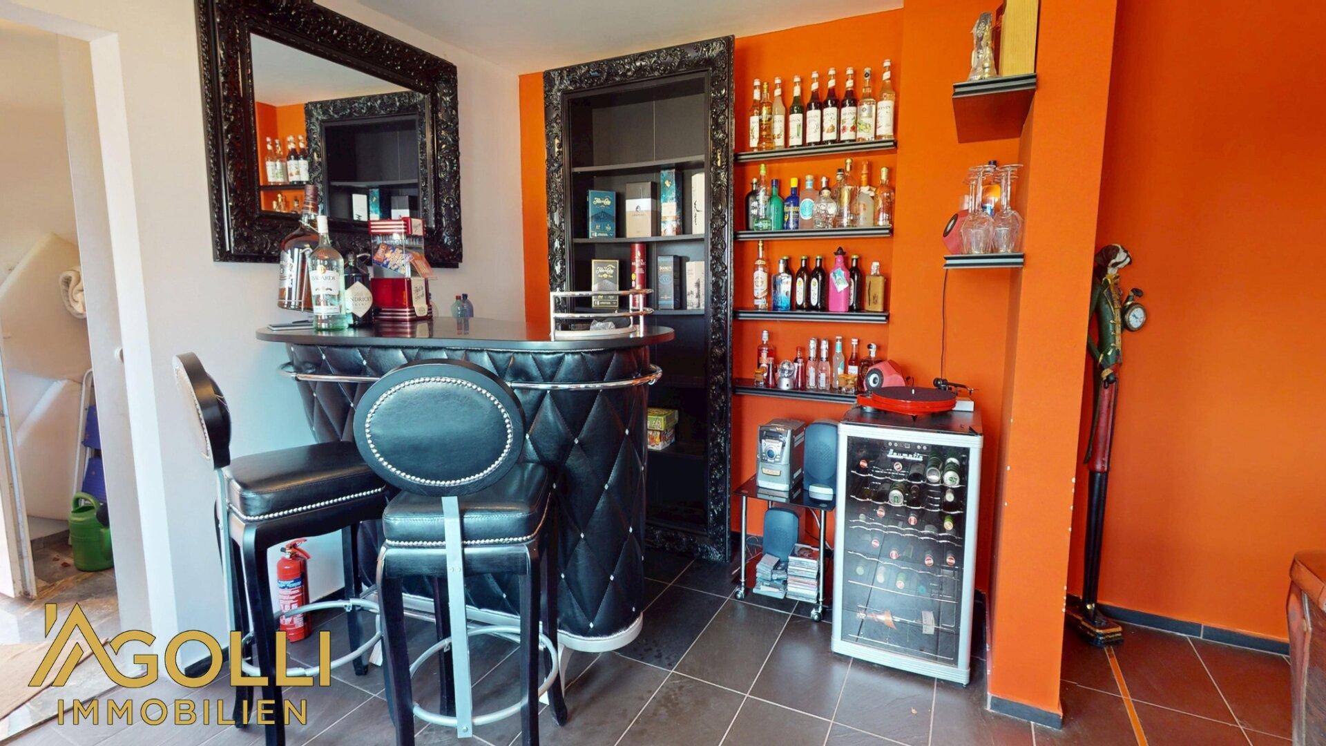 Bar-Bereich mit Weinkühler, Regalen für Getränke und stilvoller Einrichtung, perfekt für Unterhaltung.