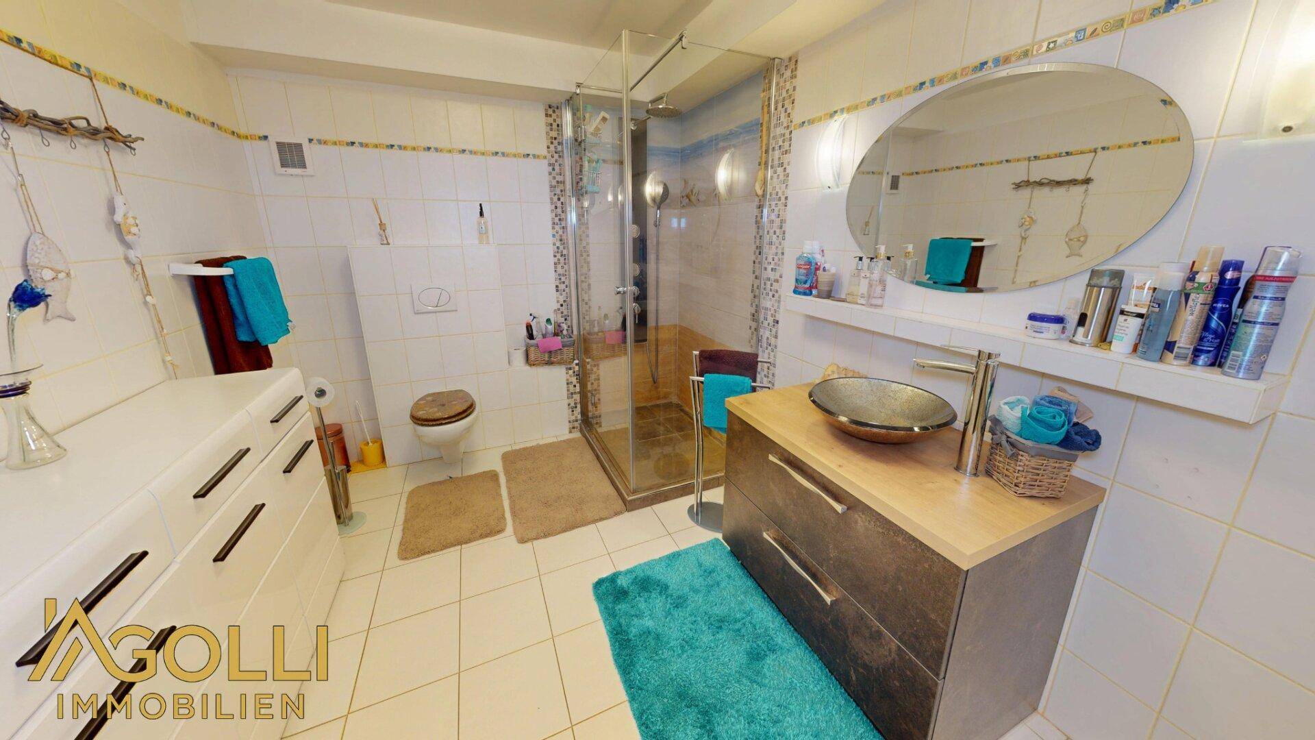 Badezimmer mit Duschkabine, modernem Waschbecken und weißen Fliesen, gut gepflegt.