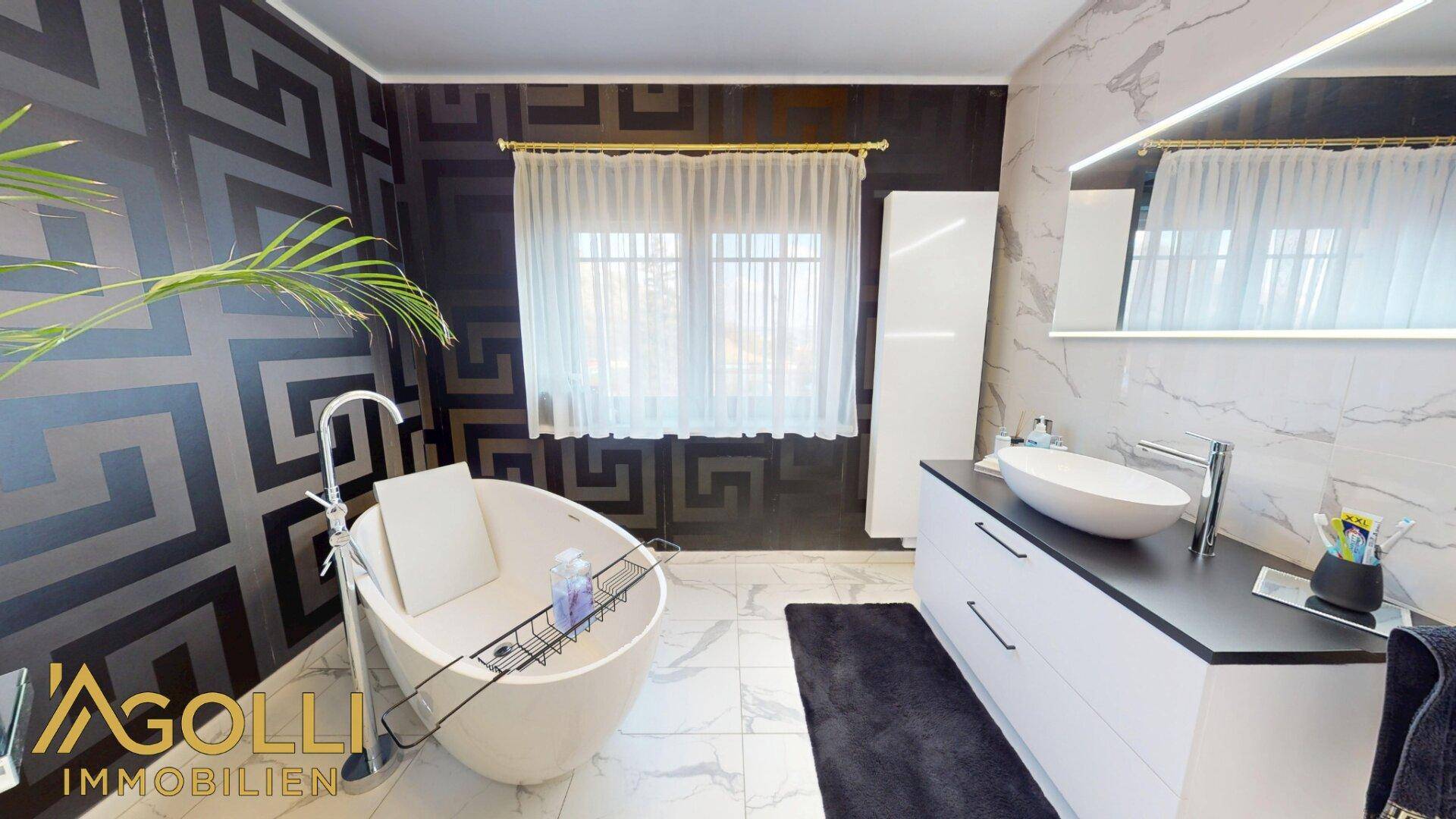 Stilvolles Badezimmer mit ovalem Waschbecken, beleuchtetem Spiegel, Fenster und beheiztem Handtuchhalter.