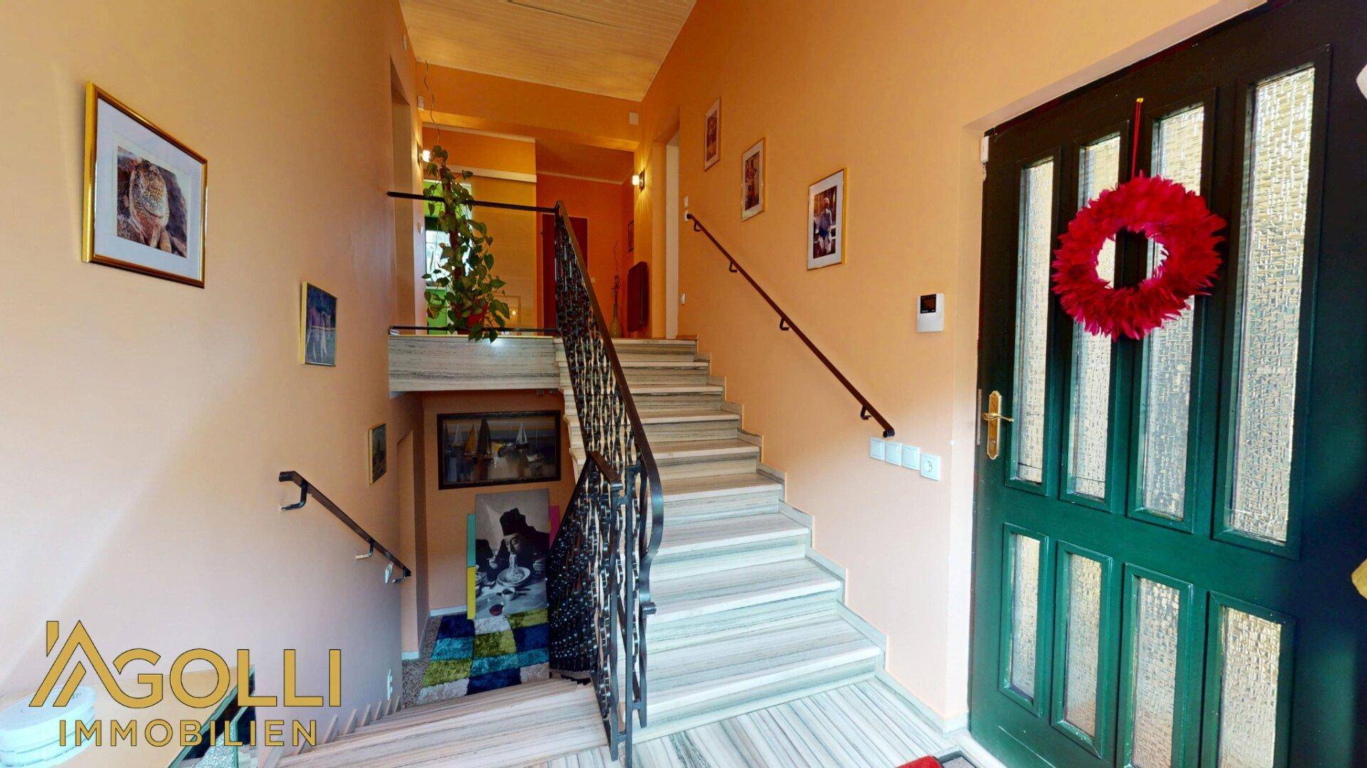 Eingangsbereich mit Treppe, Marmorstufen und dekorativer Haustür, die einen einladenden Eindruck macht.