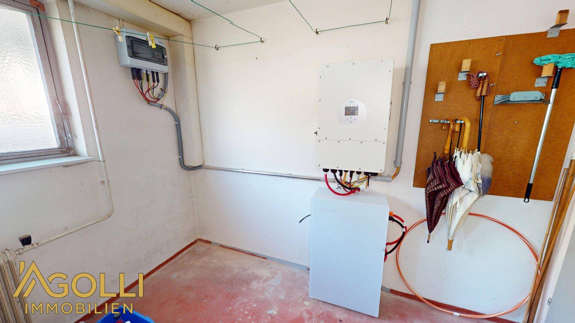 Technikraum mit Solaranlagen-Wechselrichter und elektrischen Installationen an der Wand.
