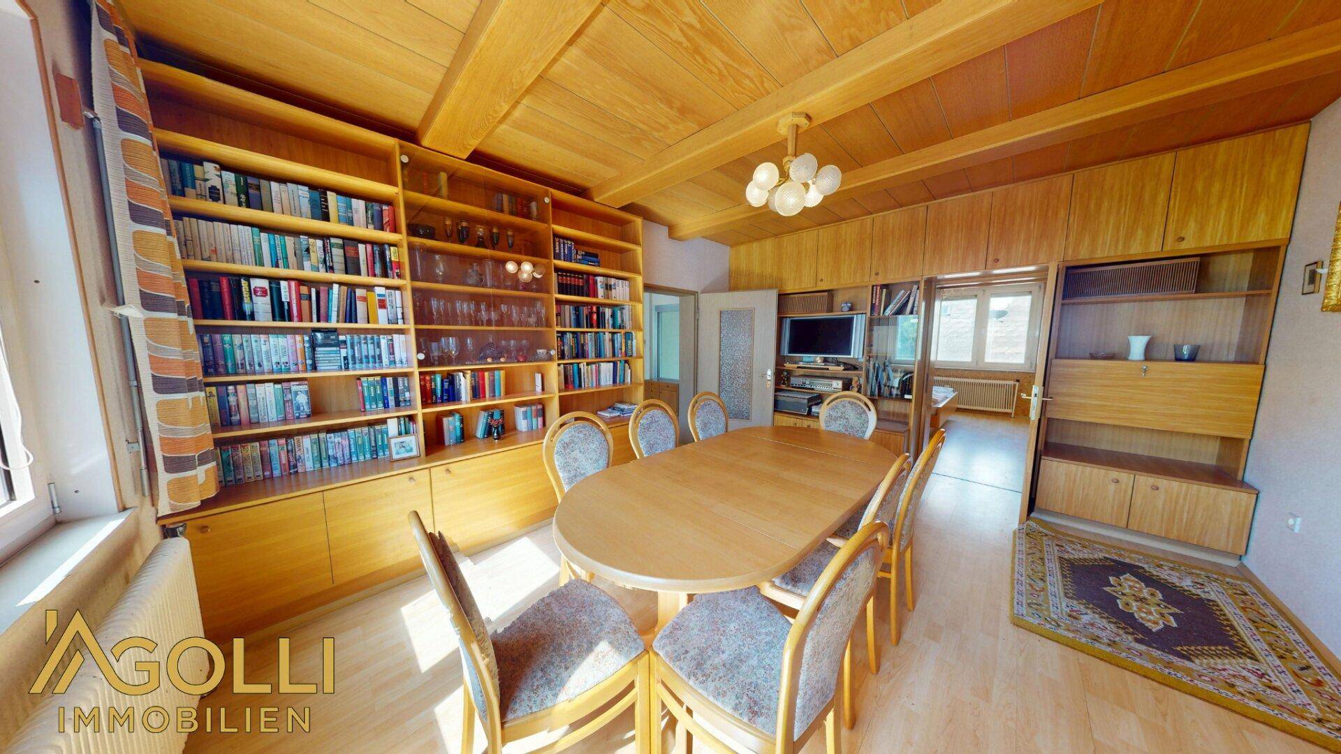 Esszimmer mit umfangreichen Einbauregalen, Holztisch und passender Holzdecke.