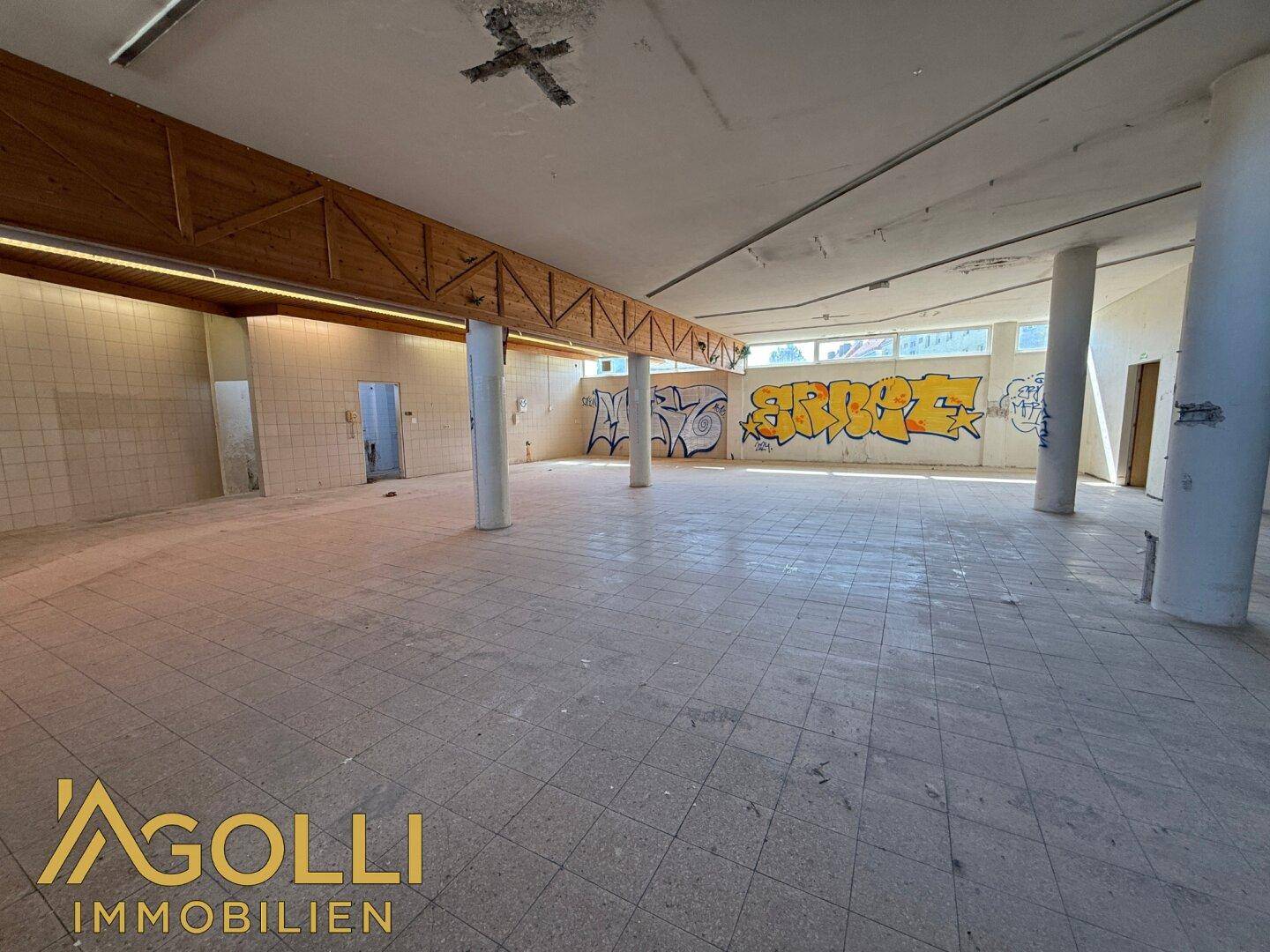 Großer, offener Raum mit Holzbalkendecke und künstlerischen Graffiti-Elementen, die eine einzigartige Atmosphäre schaffen.