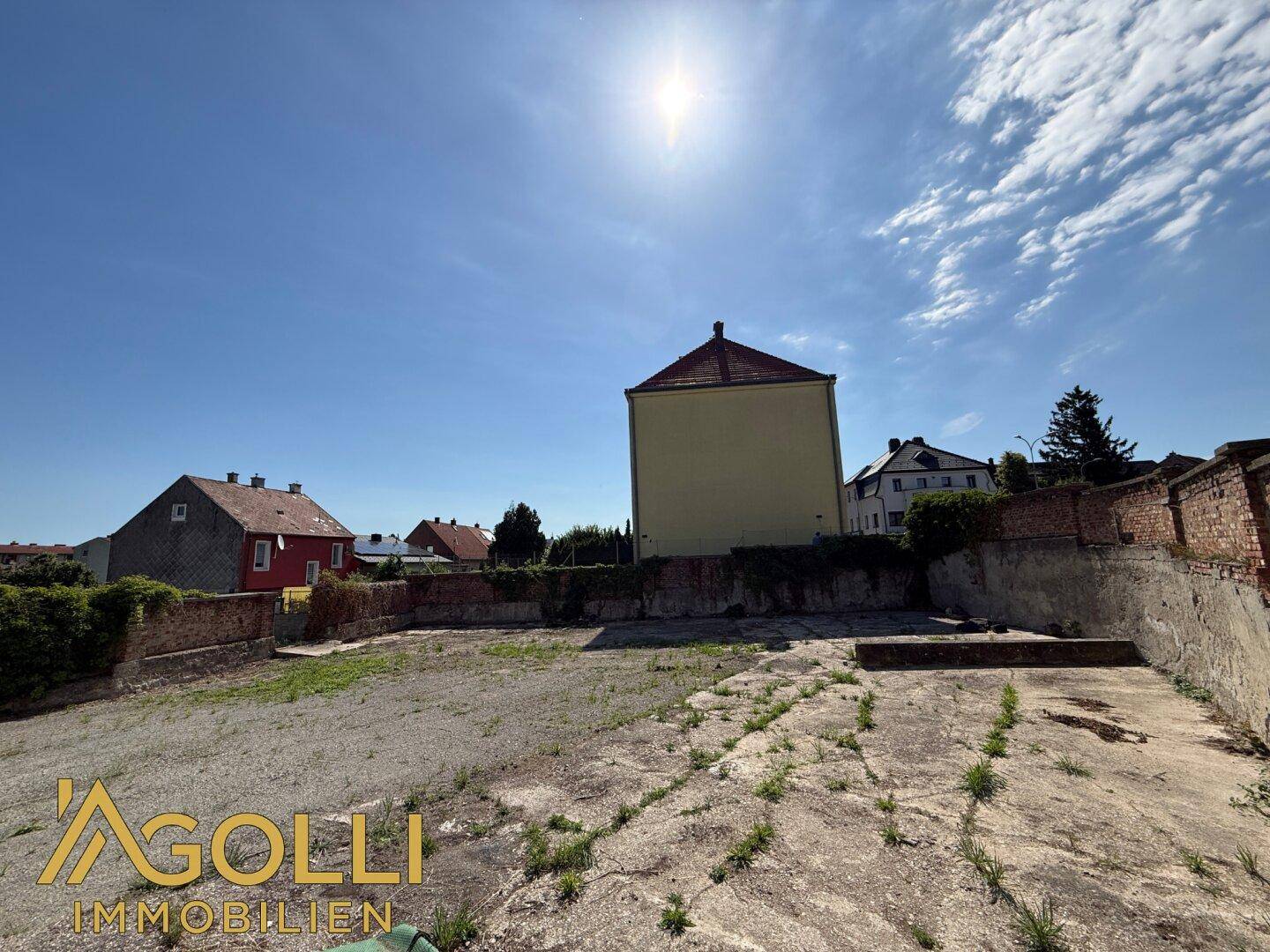 Sonniger Blick auf das weitläufige Grundstück mit dem Hauptgebäude und weiteren Häusern in der Ferne.