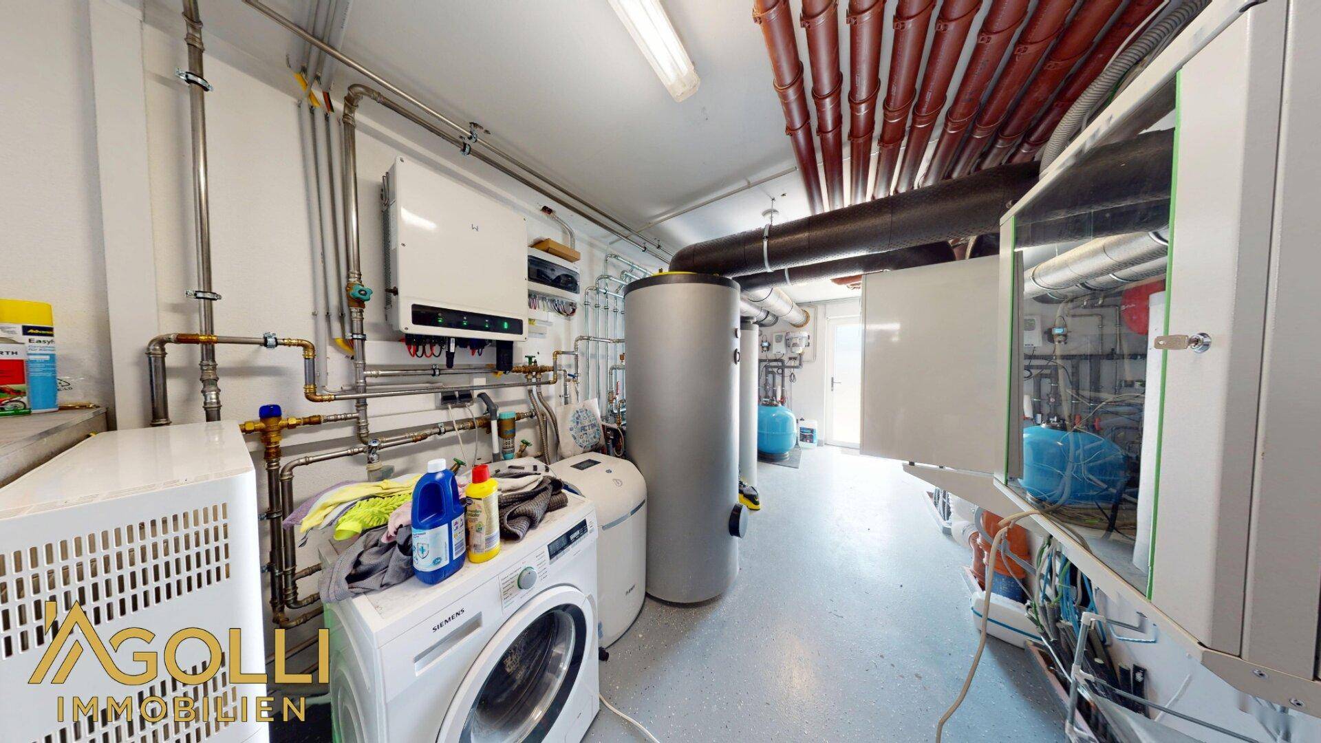 Technikraum mit Heizungsanlage, Warmwasserspeicher und Waschmaschine, gut organisiert.